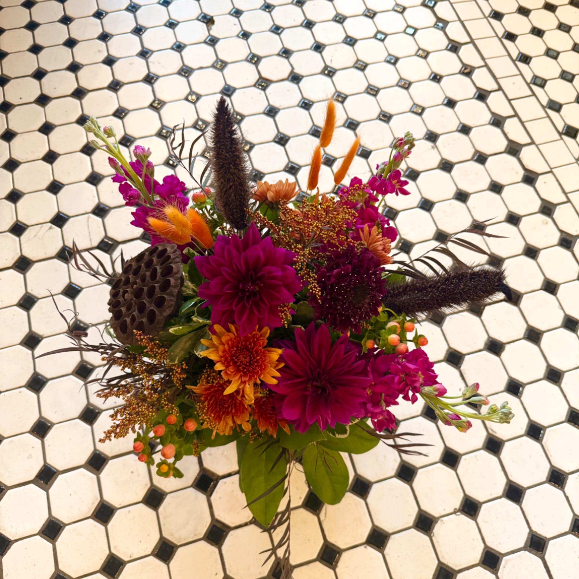 Colorful mixed bouquet with magenta and orange flowers on a tiled floor