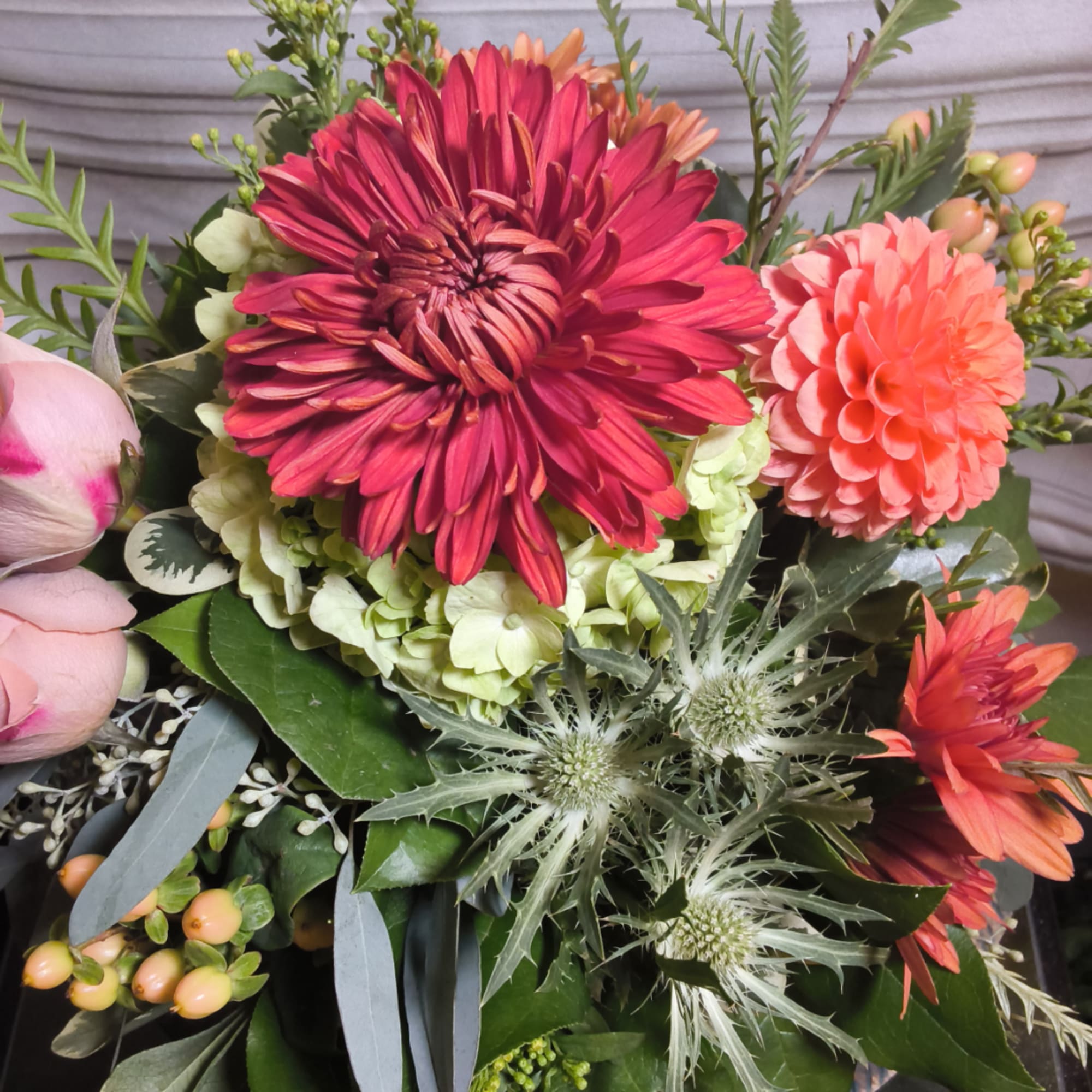 Mixed bouquet with magenta and coral blooms, pale pink buds, and spiky thistle flowers
