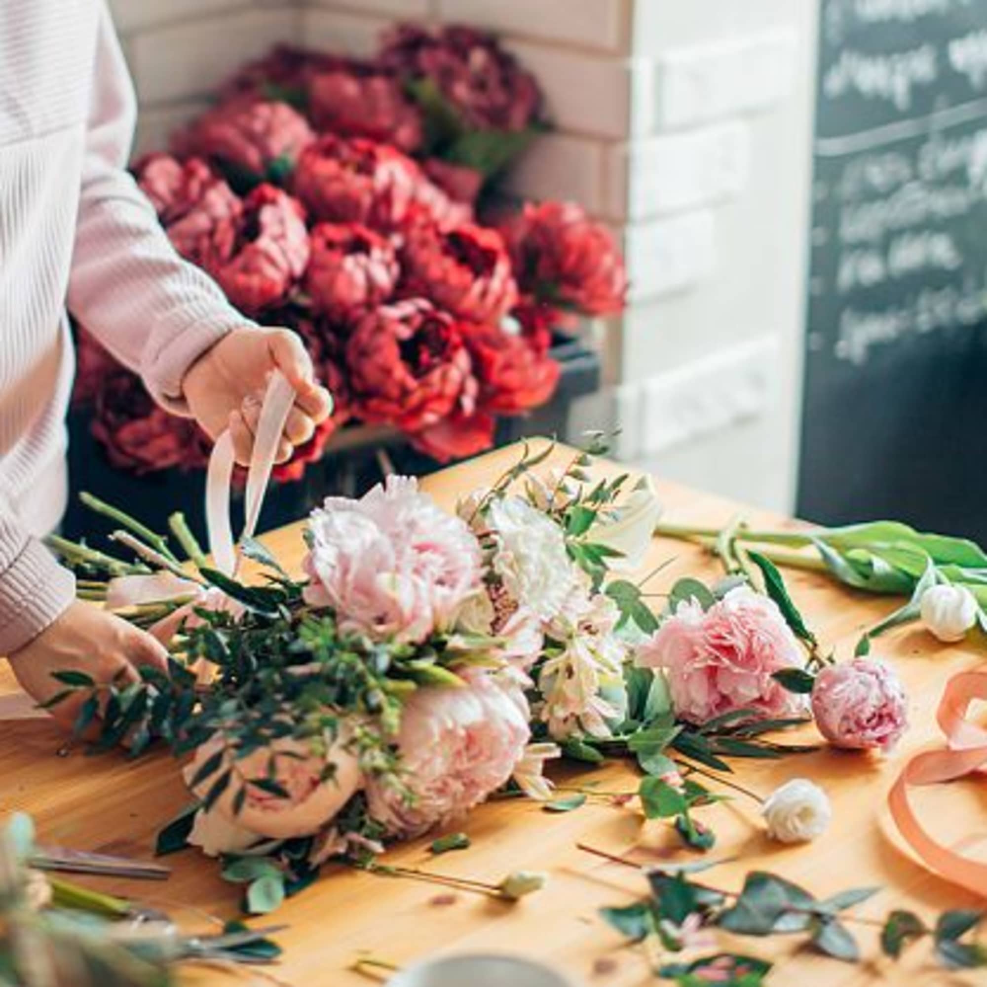 Person arranging pink and white flowers on a table