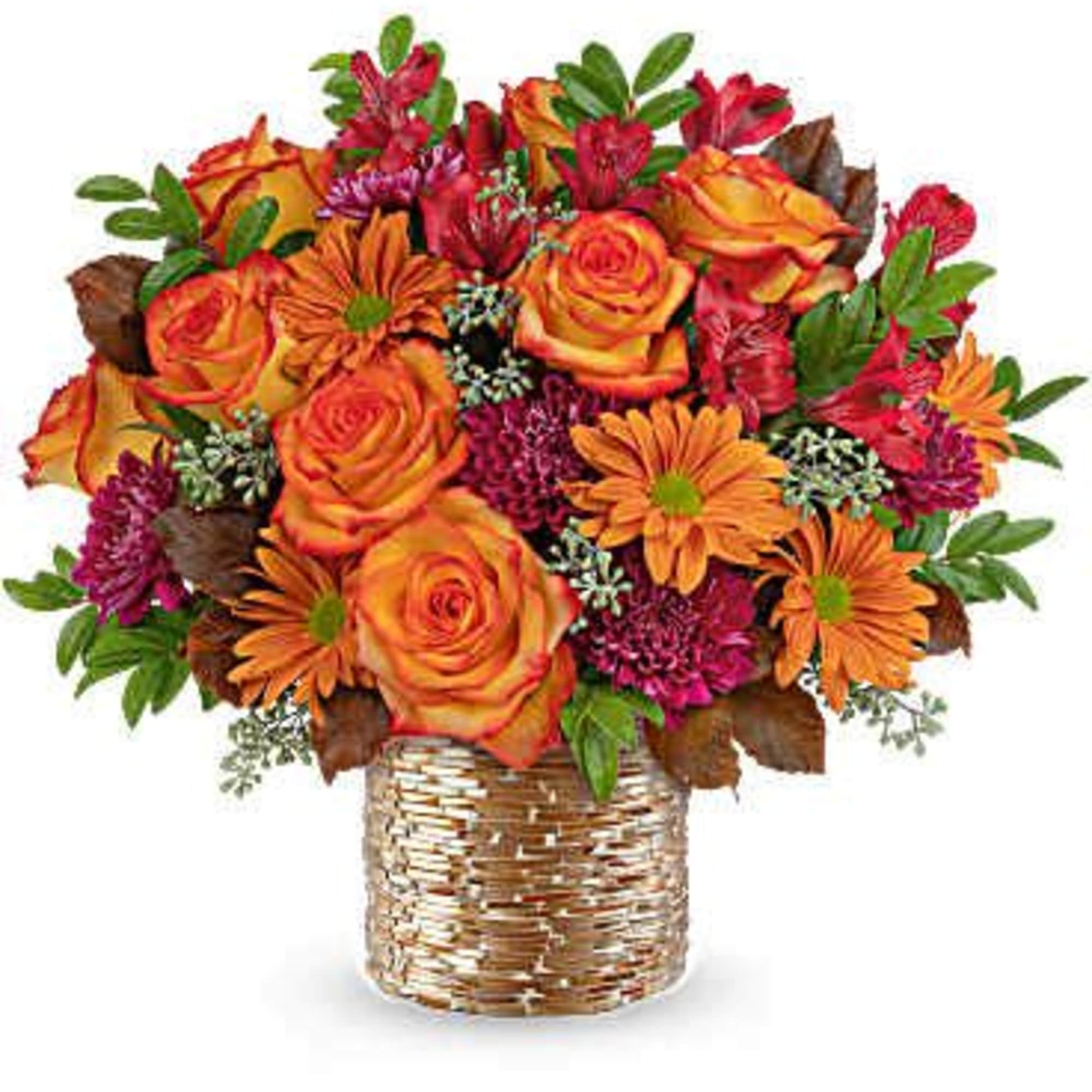 Orange roses and mixed autumn flowers in a woven basket vase