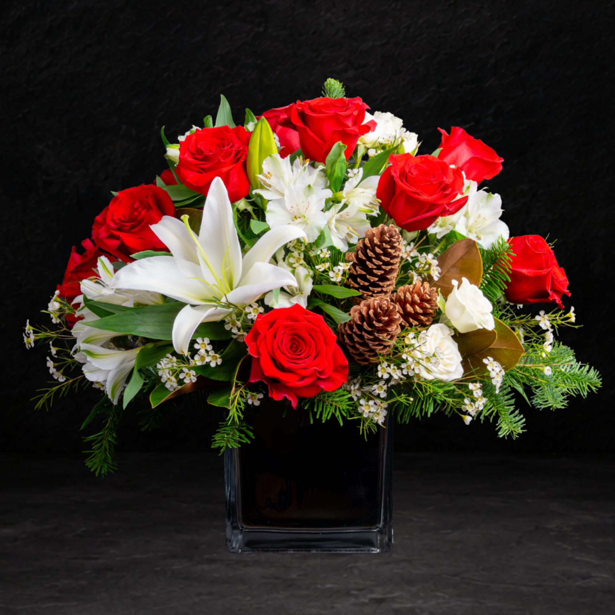 Red roses and white lilies in a clear square vase