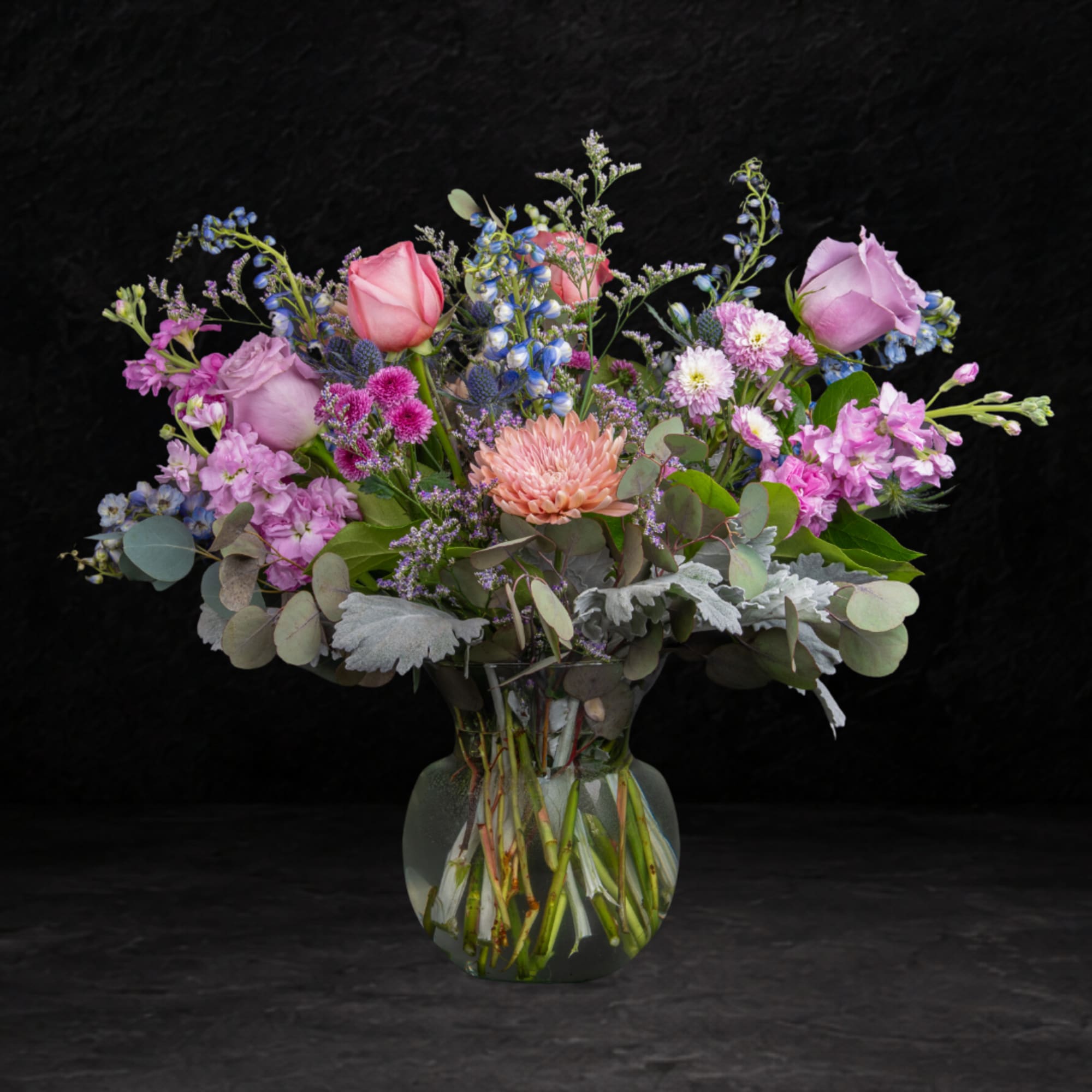 Mixed pink and lavender flowers arranged in a clear glass vase