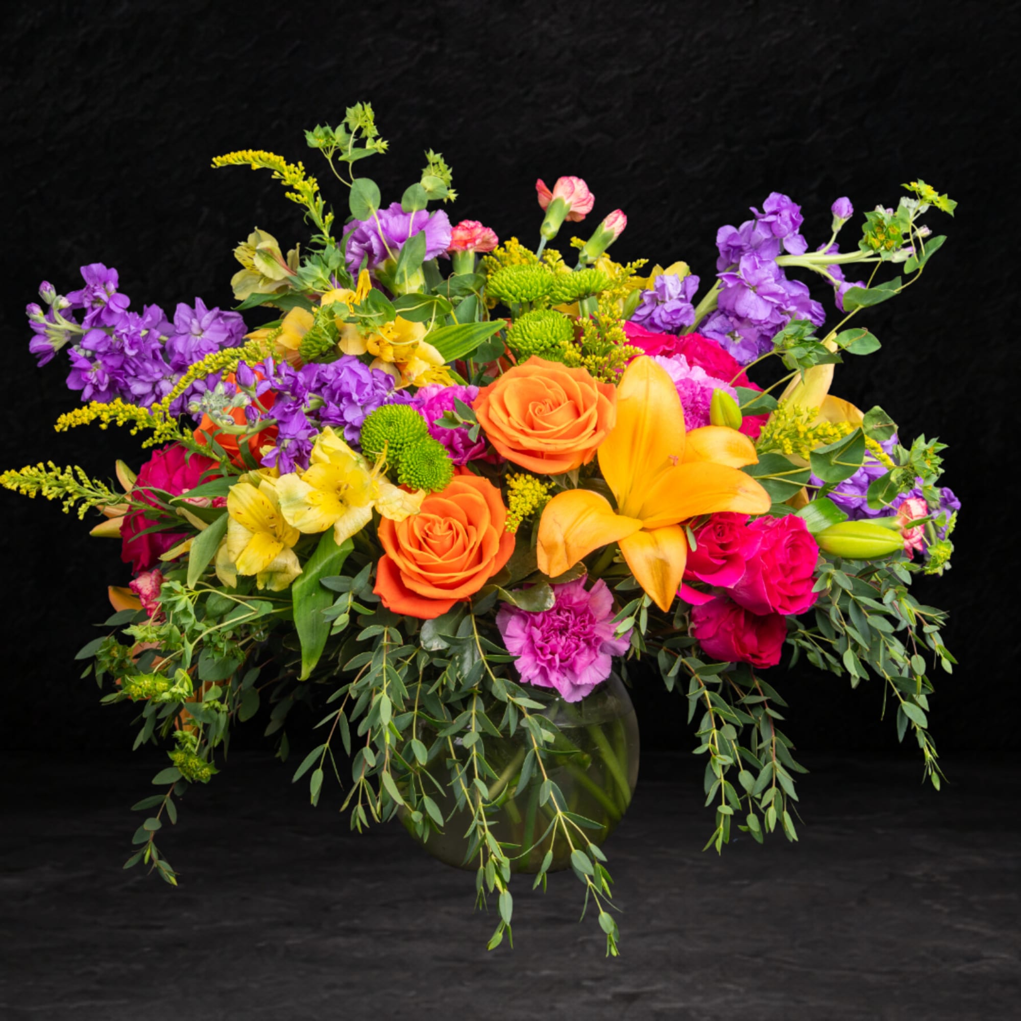 Colorful mixed bouquet in a glass vase with roses and lilies