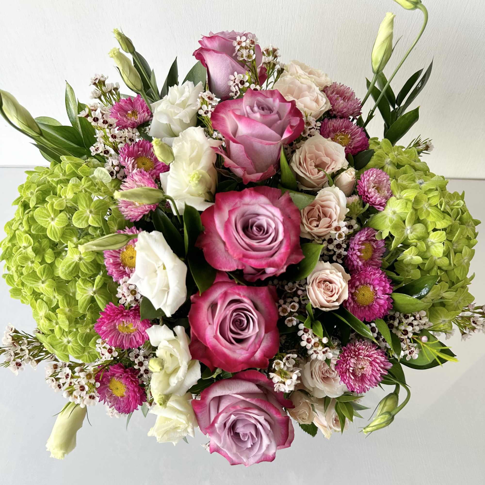 Bouquet of pink and white roses with green hydrangeas and small purple flowers