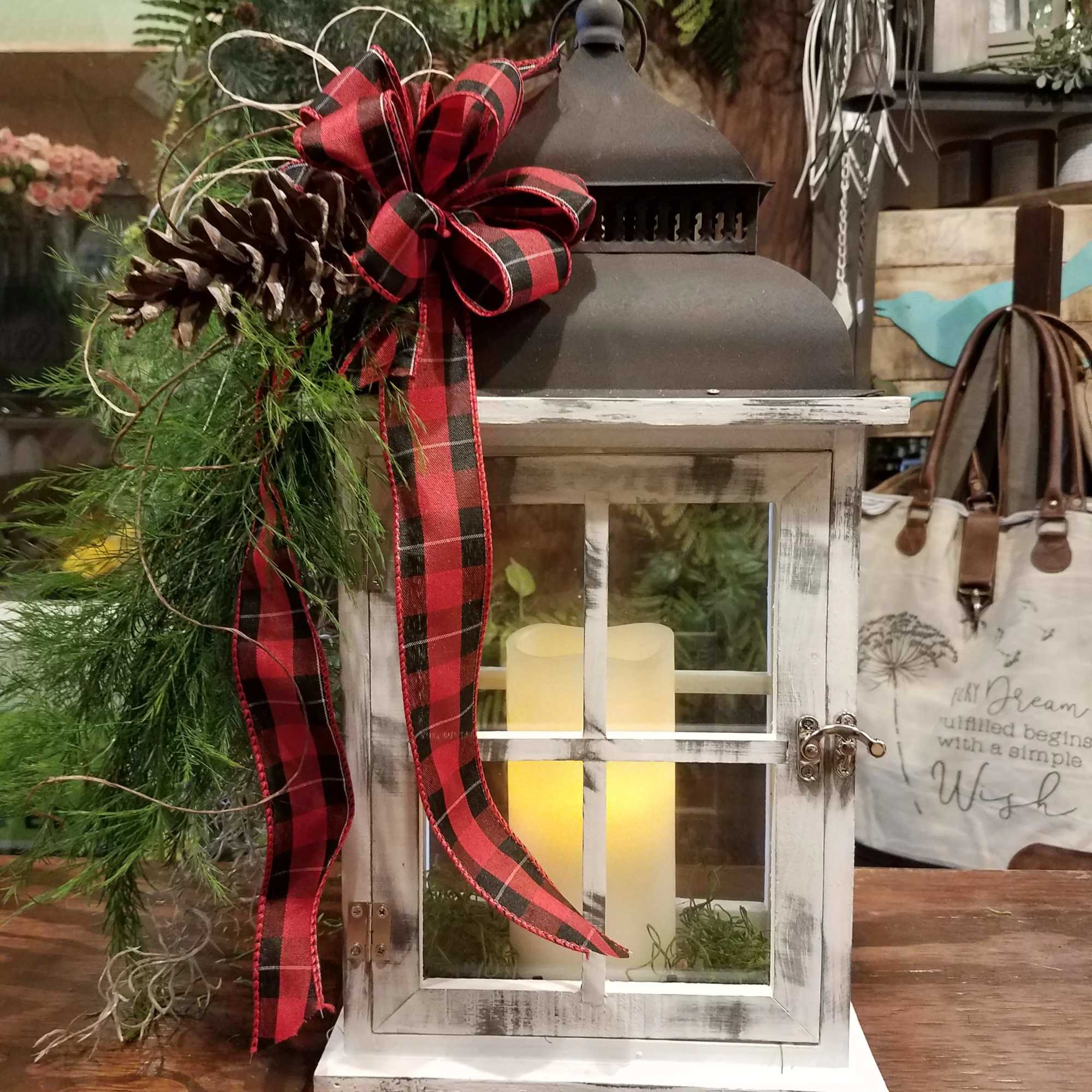 Decorative lantern with a plaid bow, pinecone, and greenery