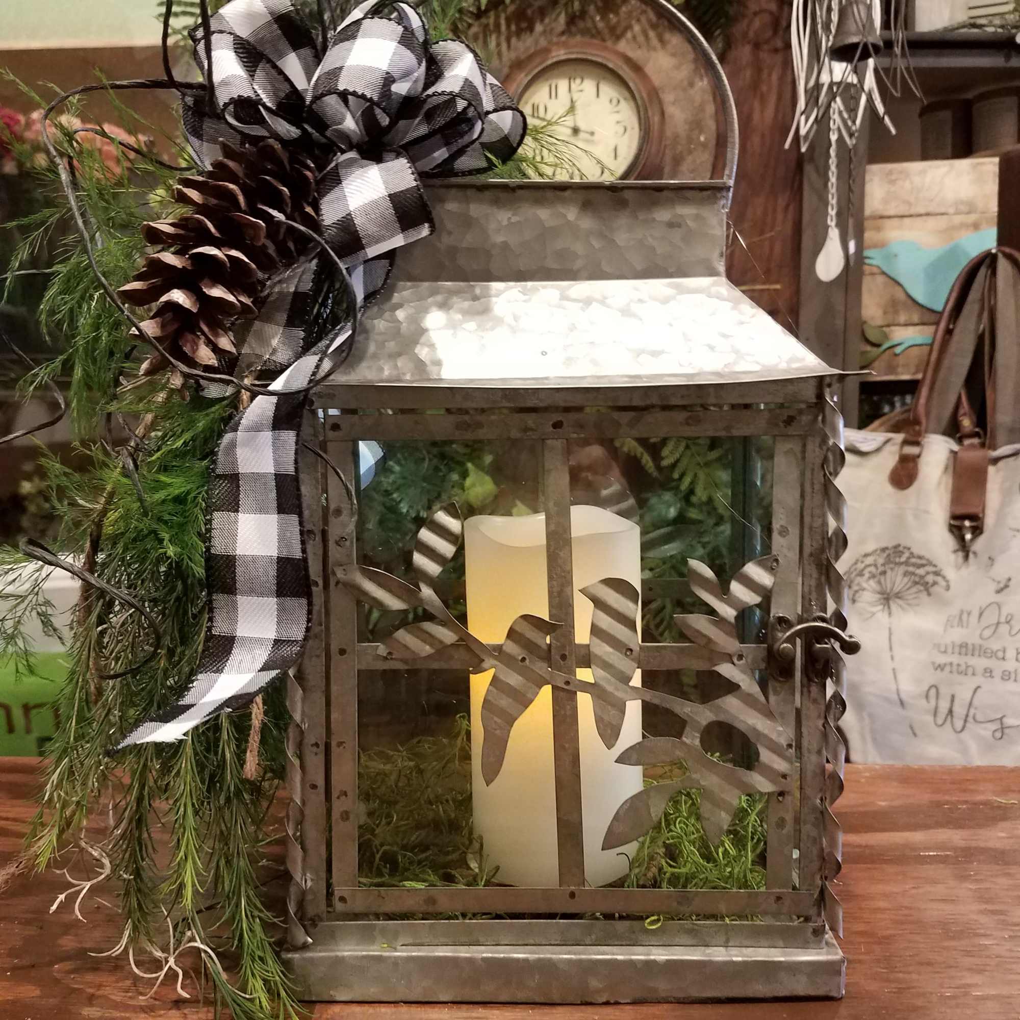 Metal lantern with candle, pinecone, and black-and-white ribbon