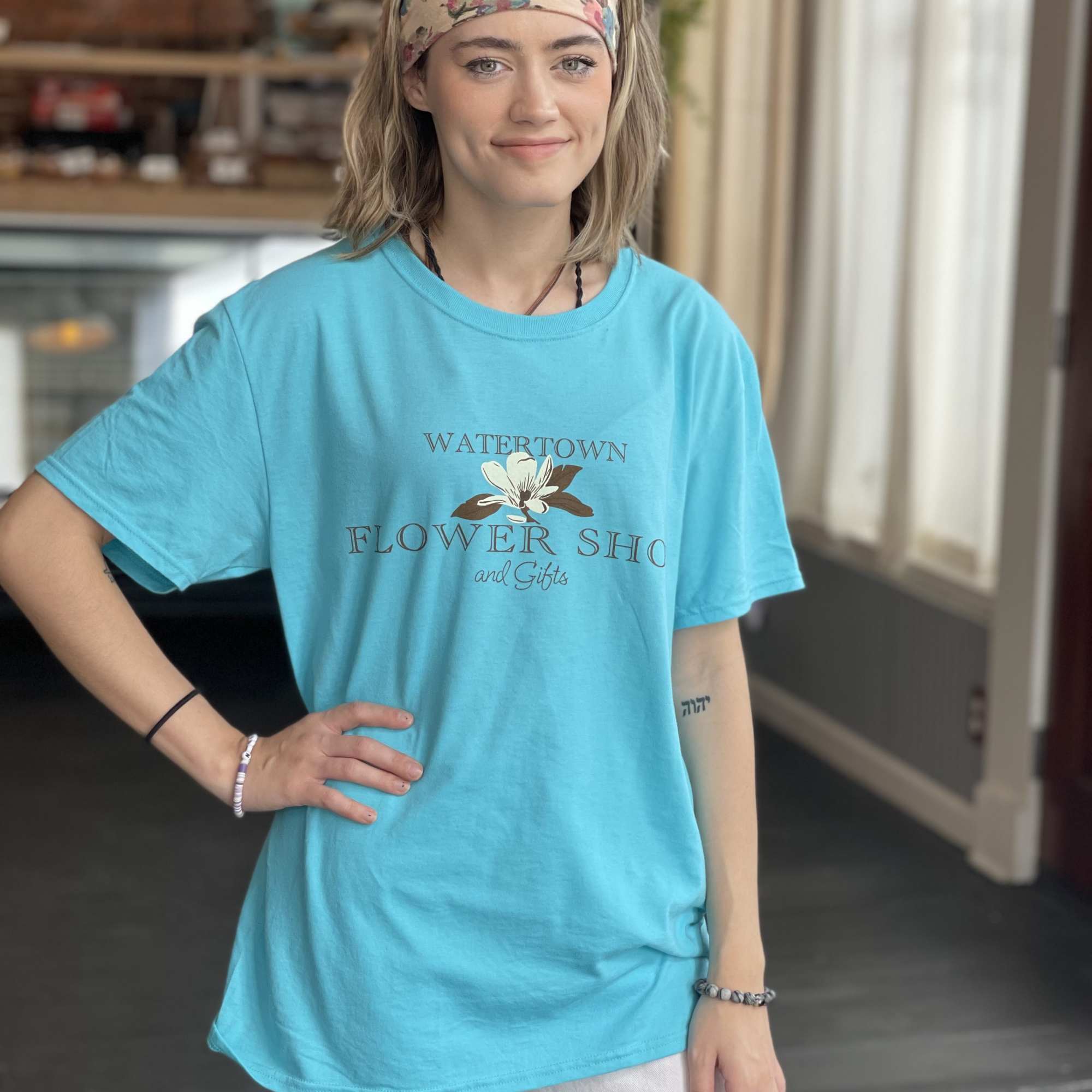 Woman wearing a turquoise flower shop T-shirt and floral headband