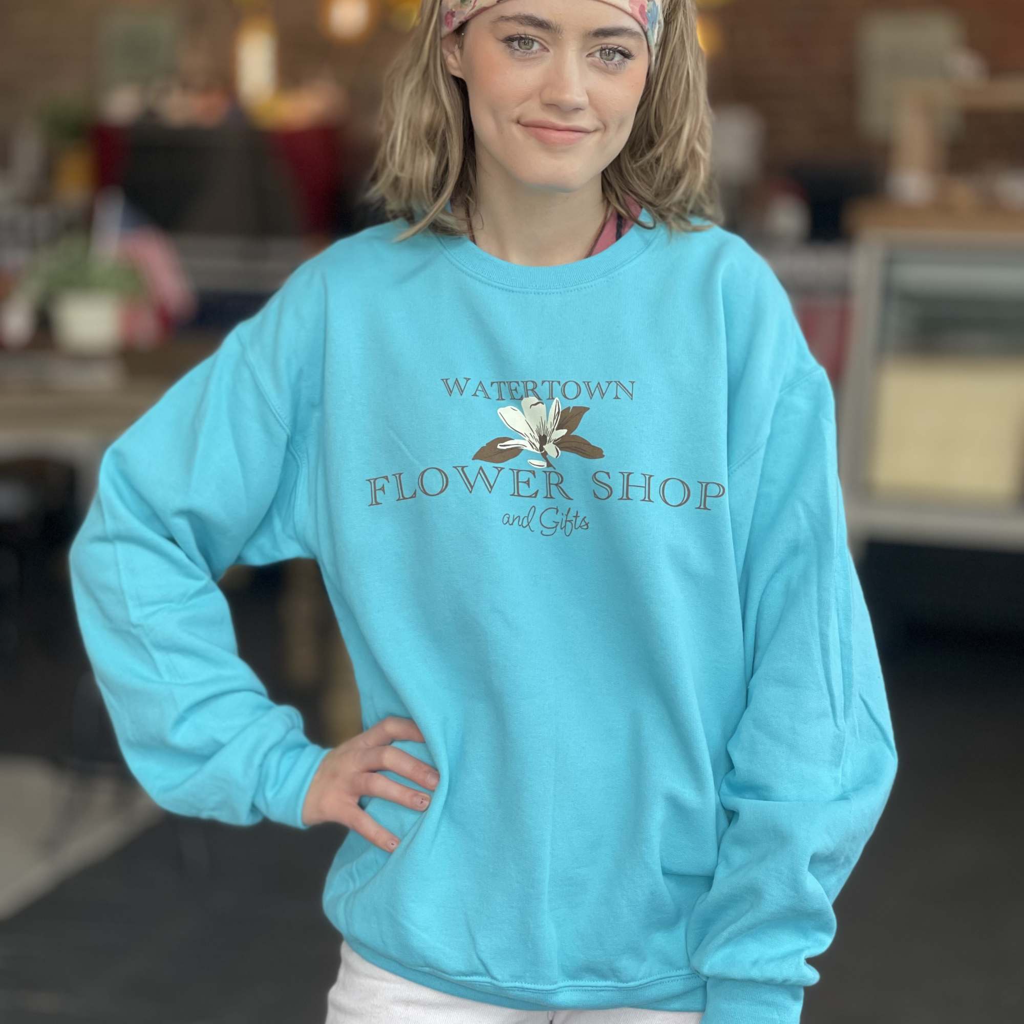 Woman wearing a turquoise flower shop sweatshirt and floral headband