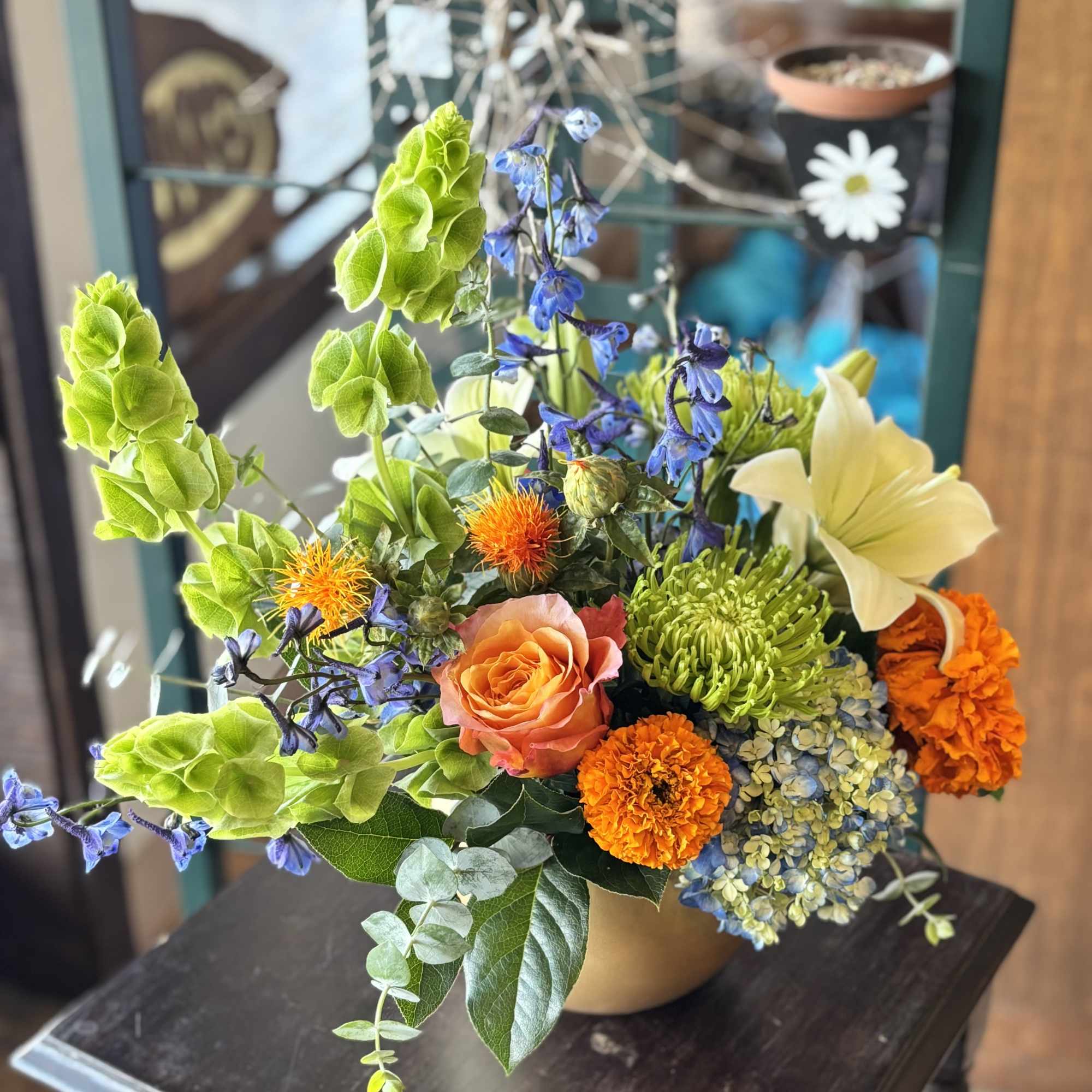 Mixed bouquet in a vase with orange, blue, green, and cream flowers