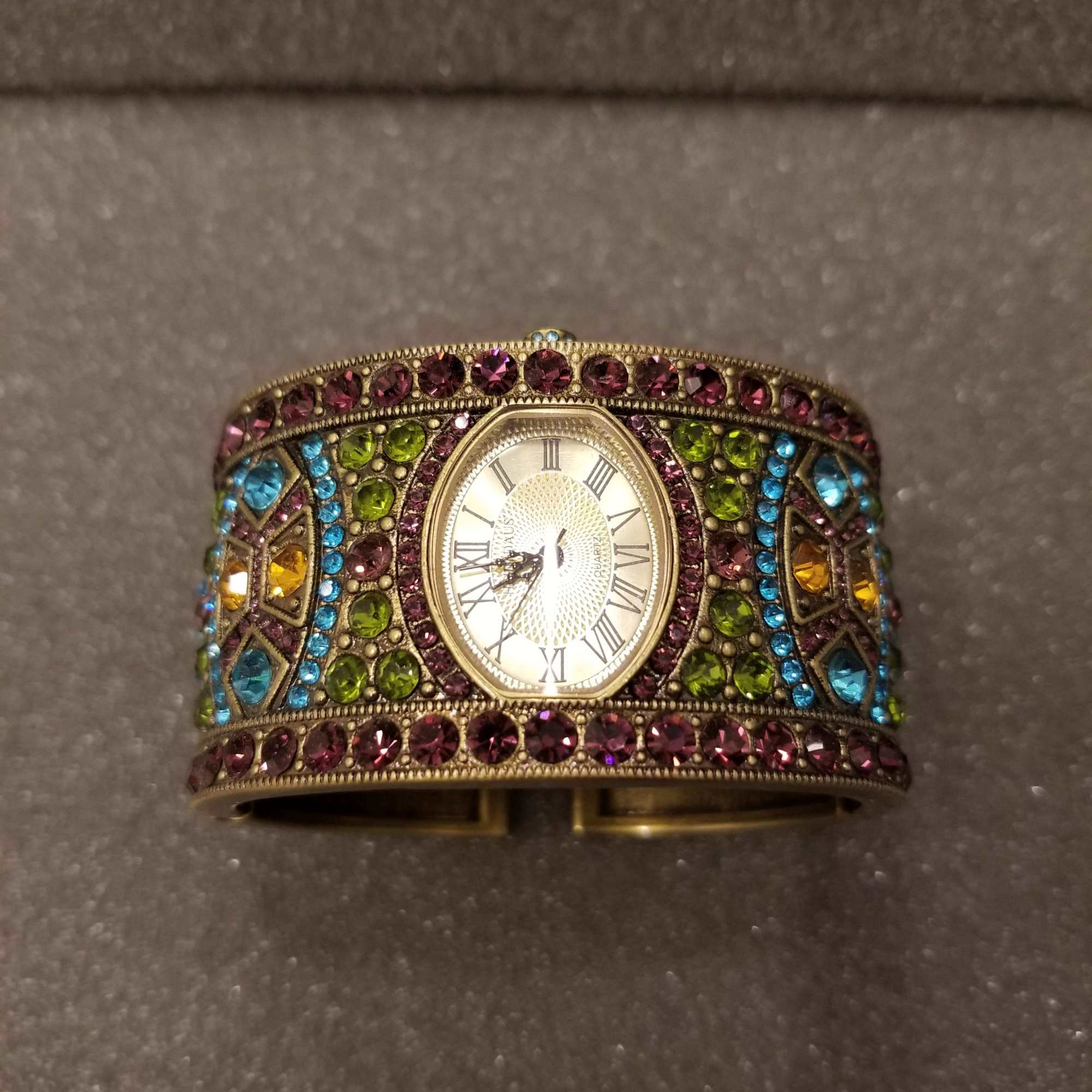 Jeweled wristwatch with a gold-toned face and multicolored stones