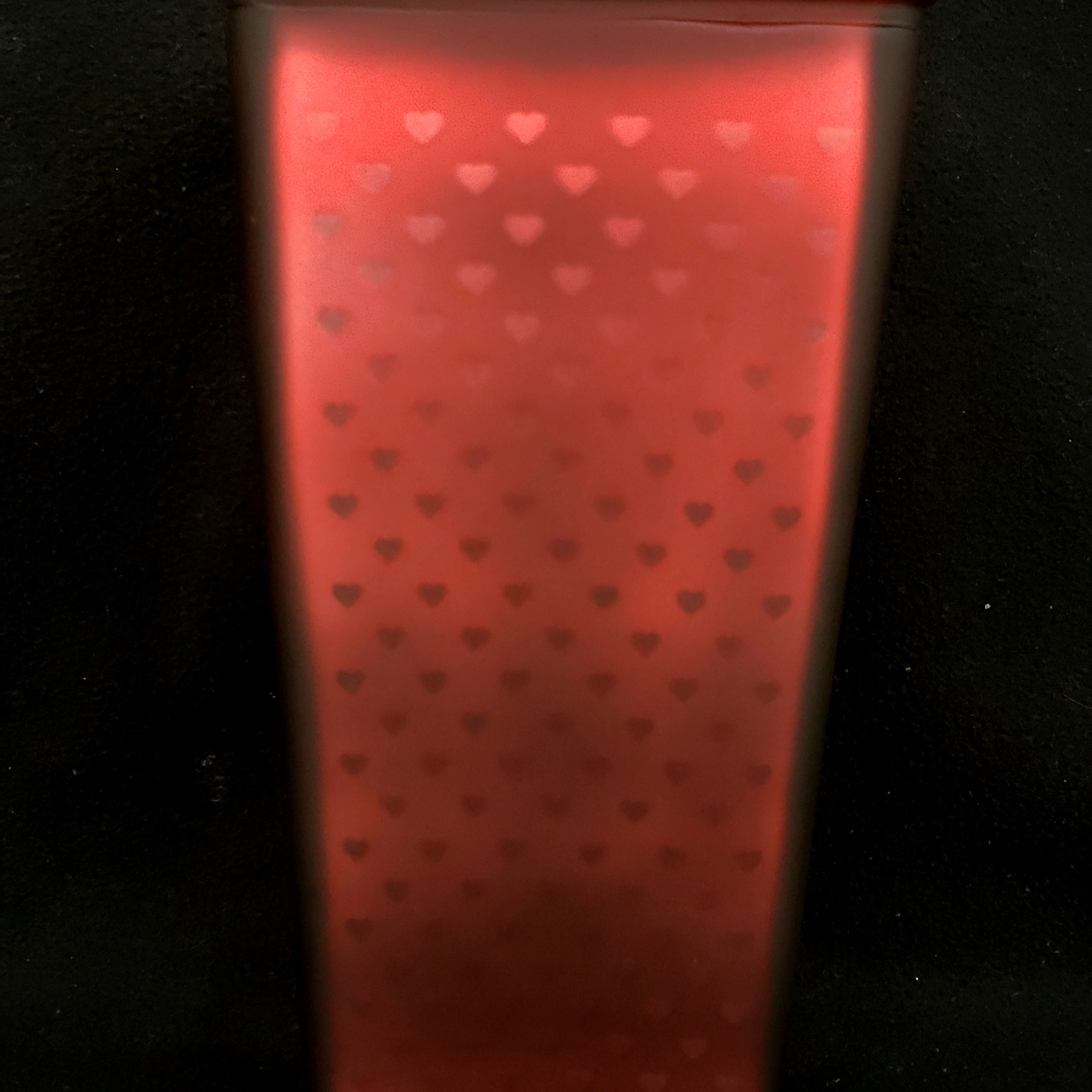 Red rectangular tin with small heart cutouts on a black background
