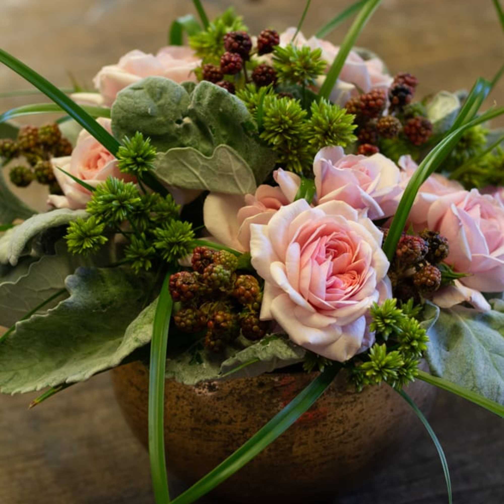 Pink roses arranged in a low bowl with green accents