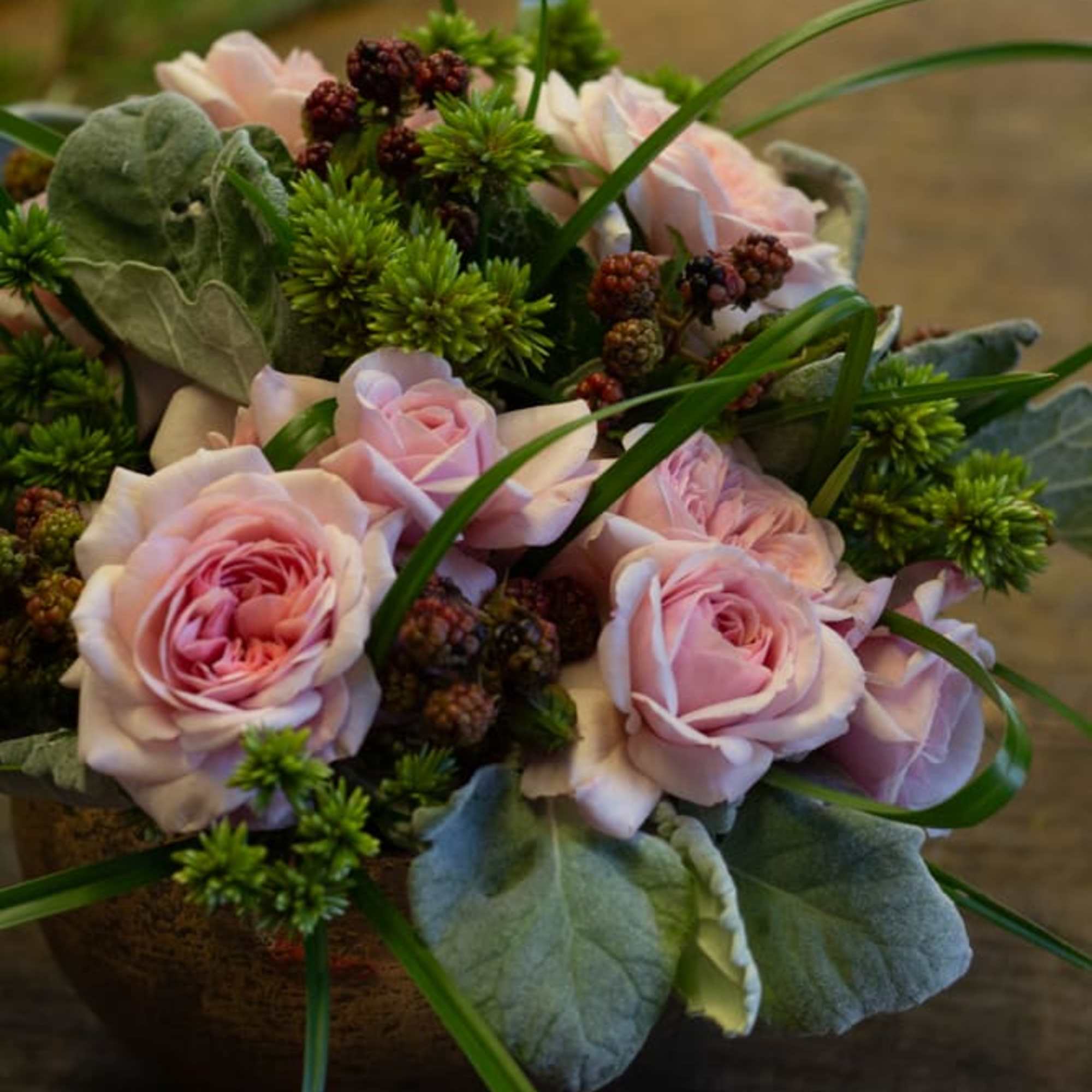 Pink roses arranged with green accents in a low bouquet.