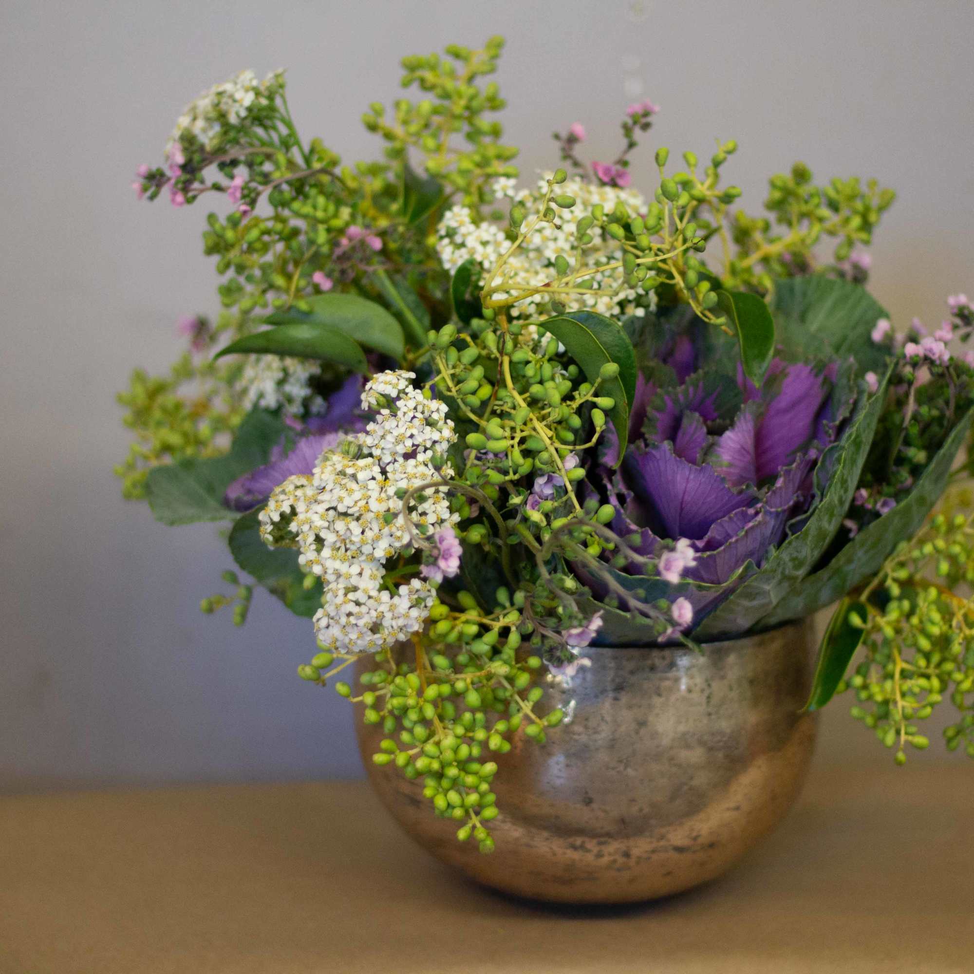 Purple and white floral arrangement in a metal bowl vase