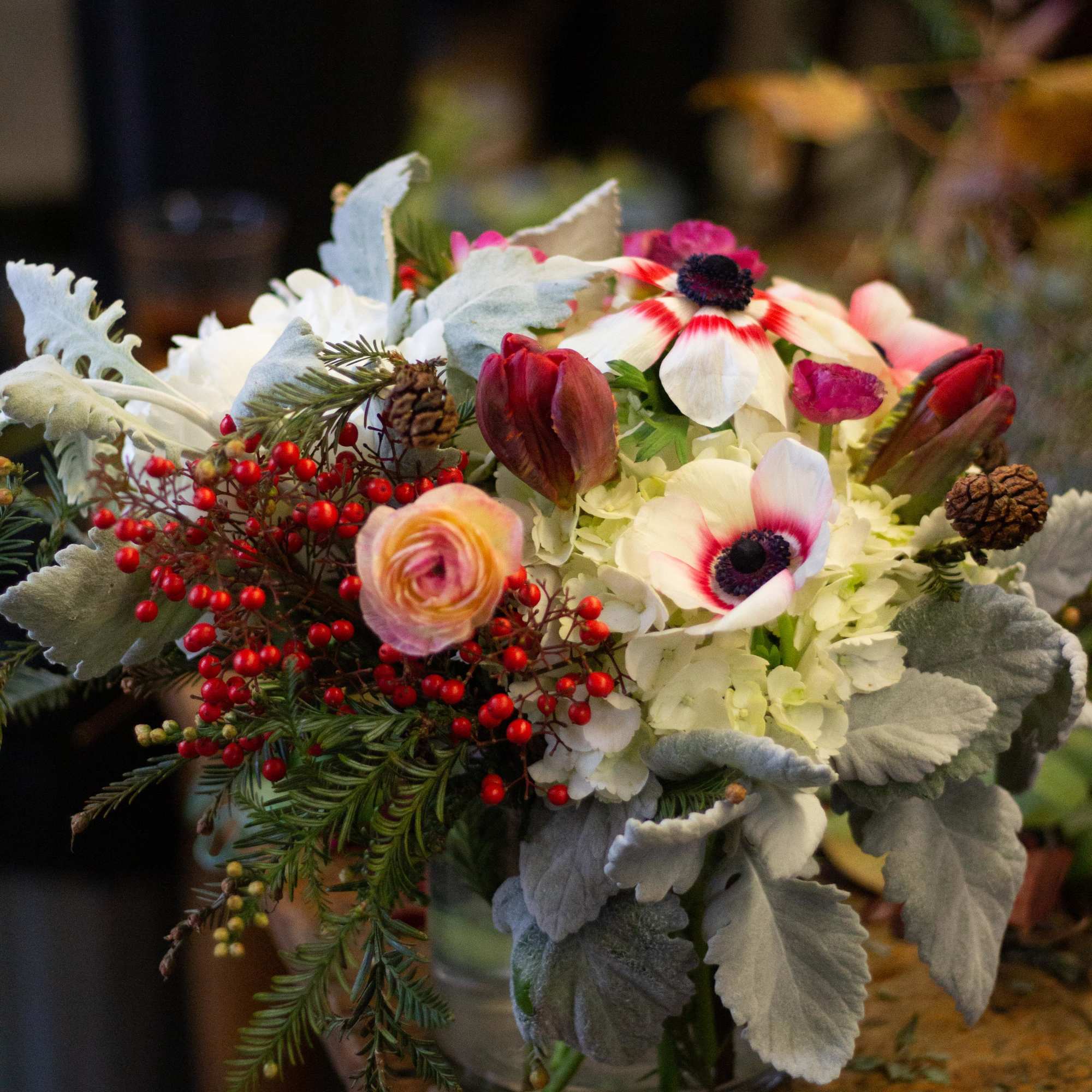 Bouquet of white and pink flowers with red berries in a glass vase