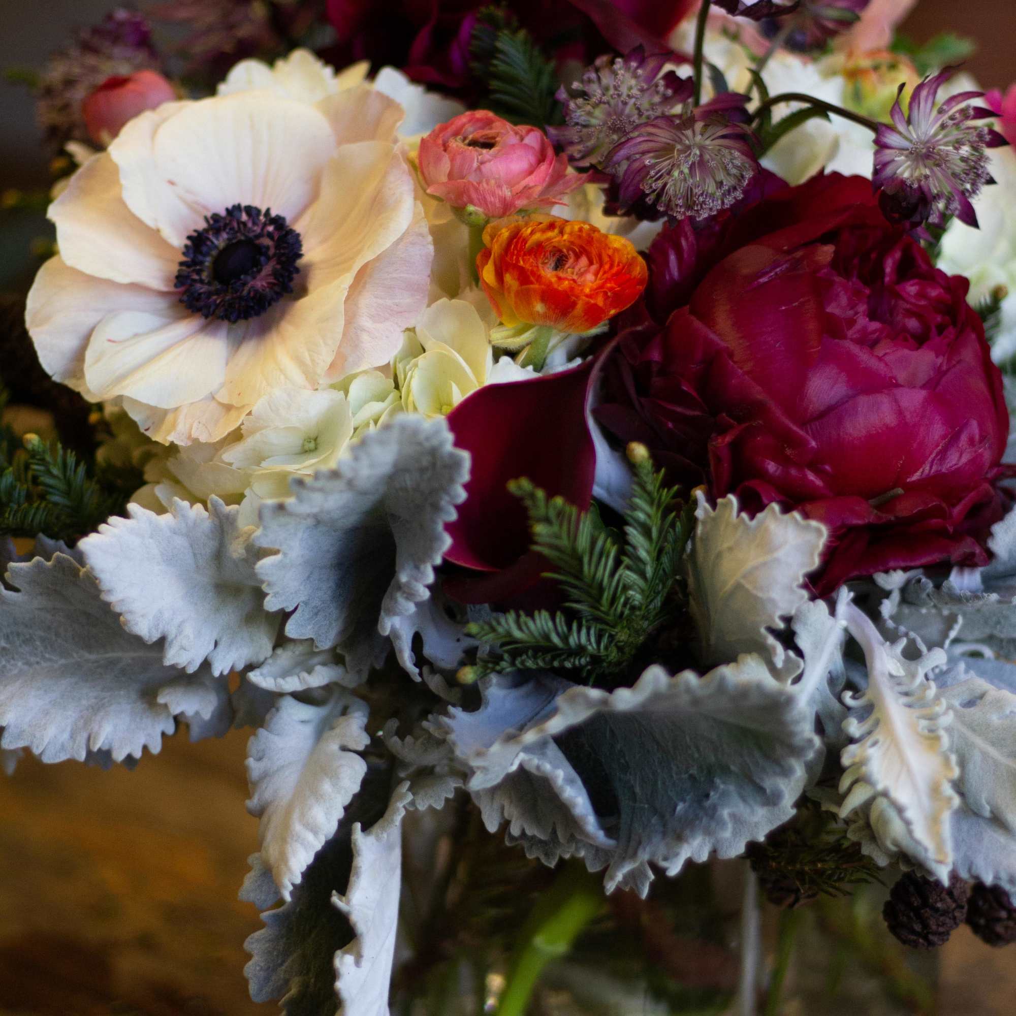 A lush arrangement with rose and plum colored flowers. 