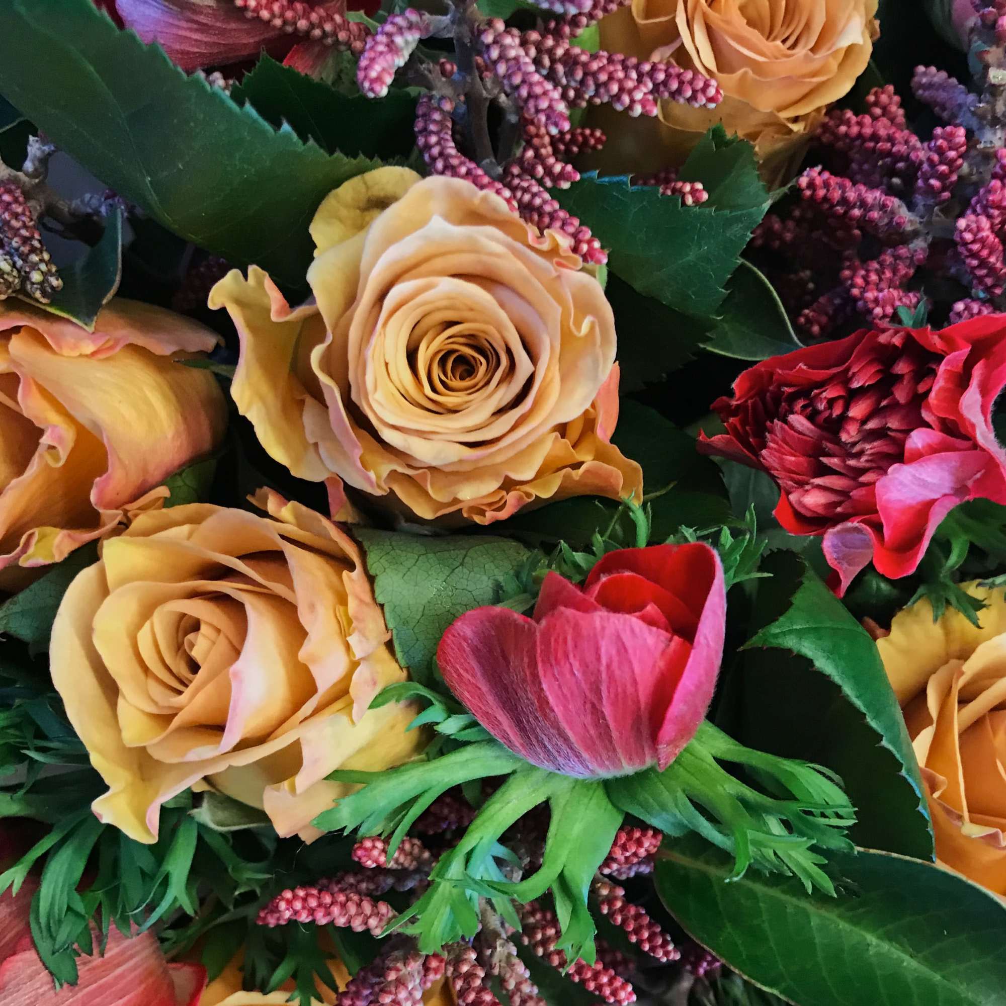 Close-up bouquet of peach and red roses with pink accent flowers