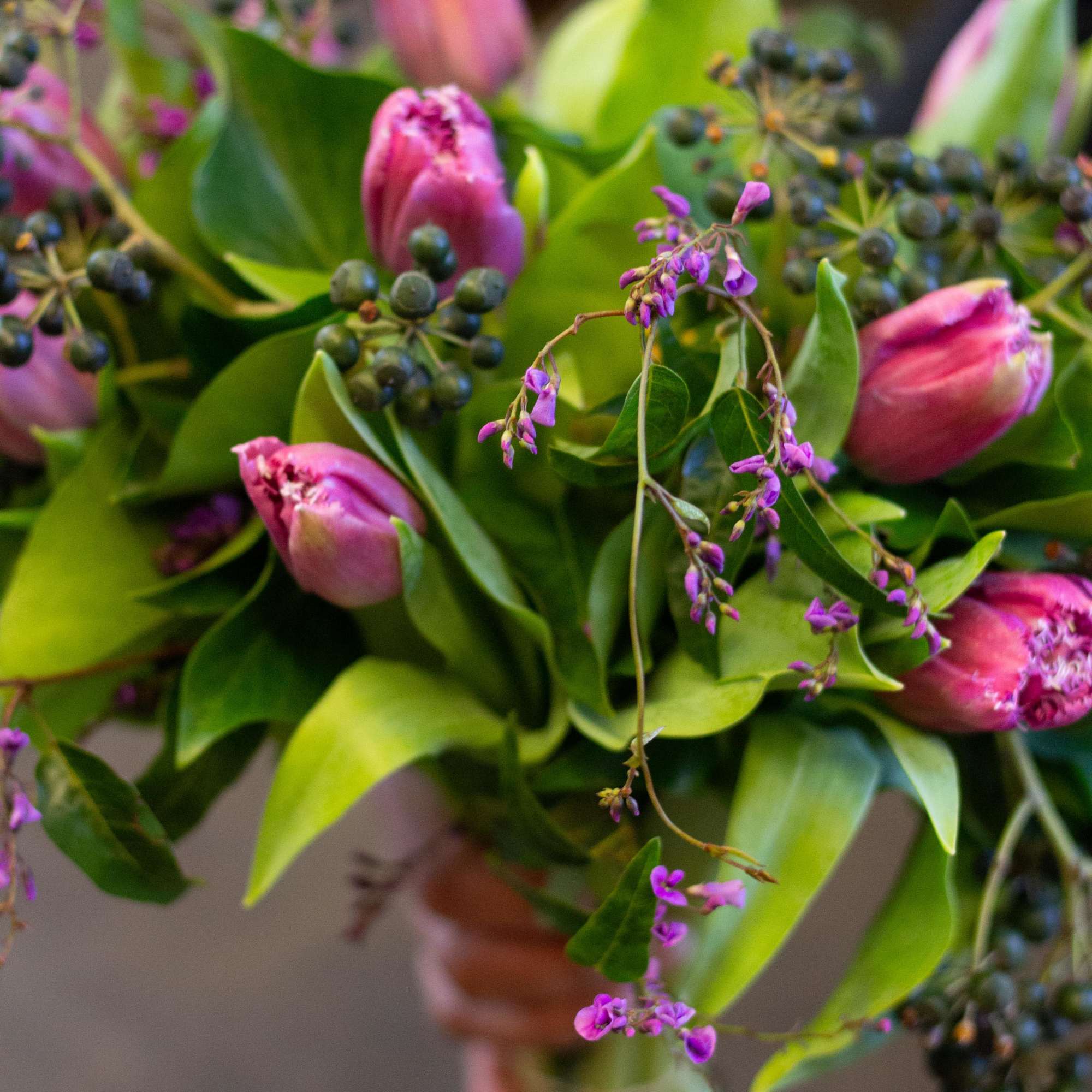 Pink tulips with purple accents and broad green leaves in a bouquet