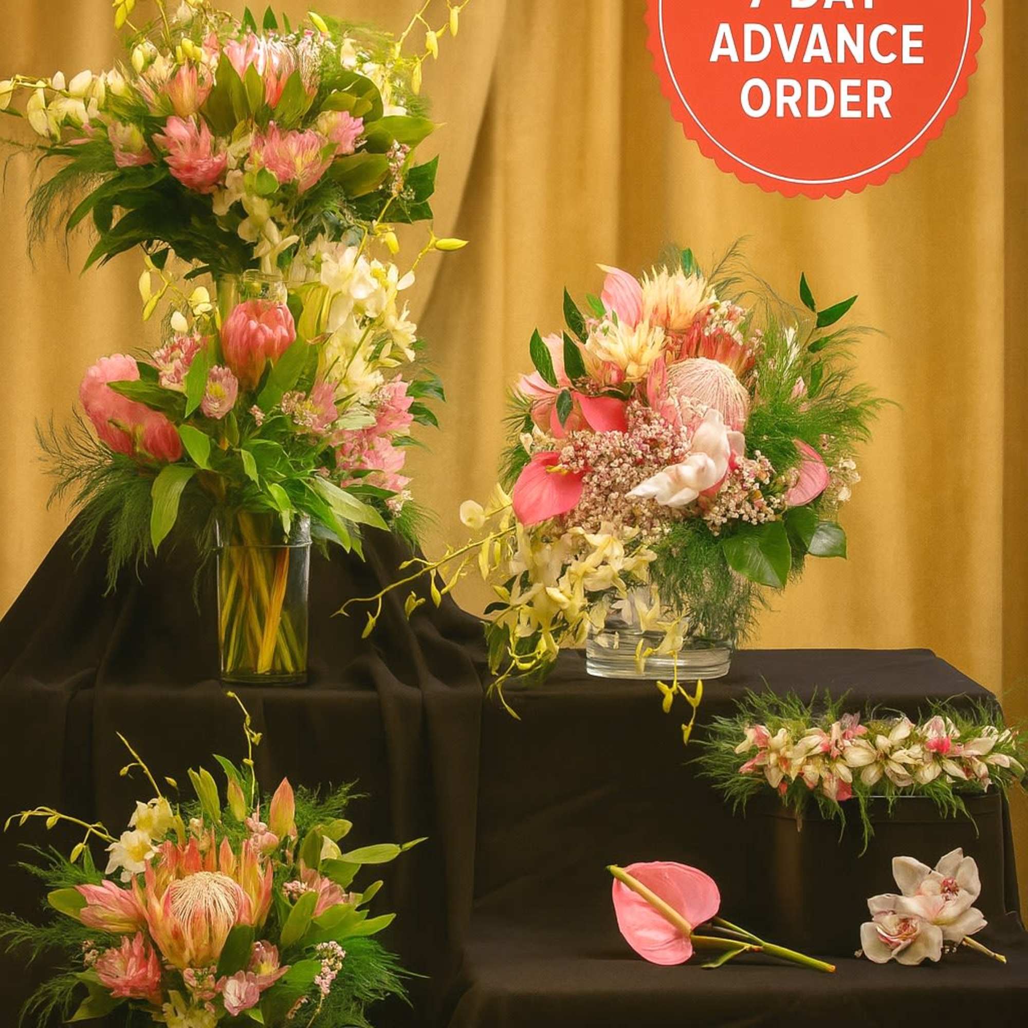 Set of pink and white tropical floral arrangements in clear glass vases on black stands.