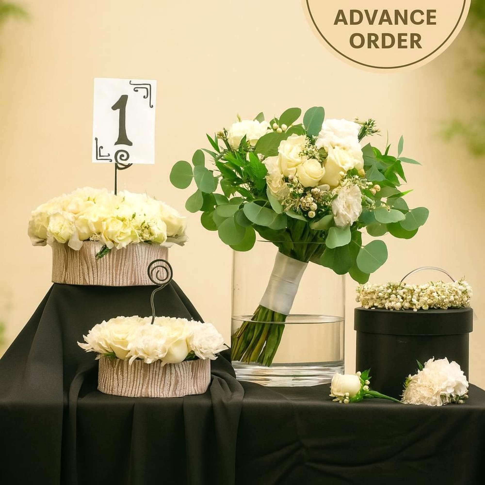 White rose wedding bouquet with matching centerpieces and floral crown on a black-draped table