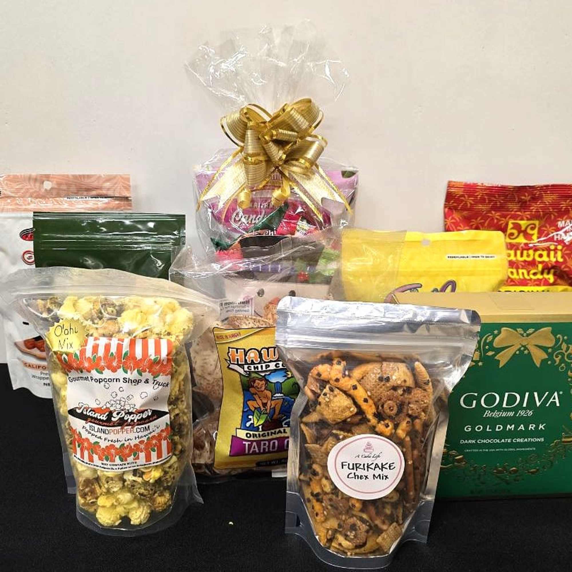 Assorted packaged snacks and a Godiva chocolate box arranged as a gift set.