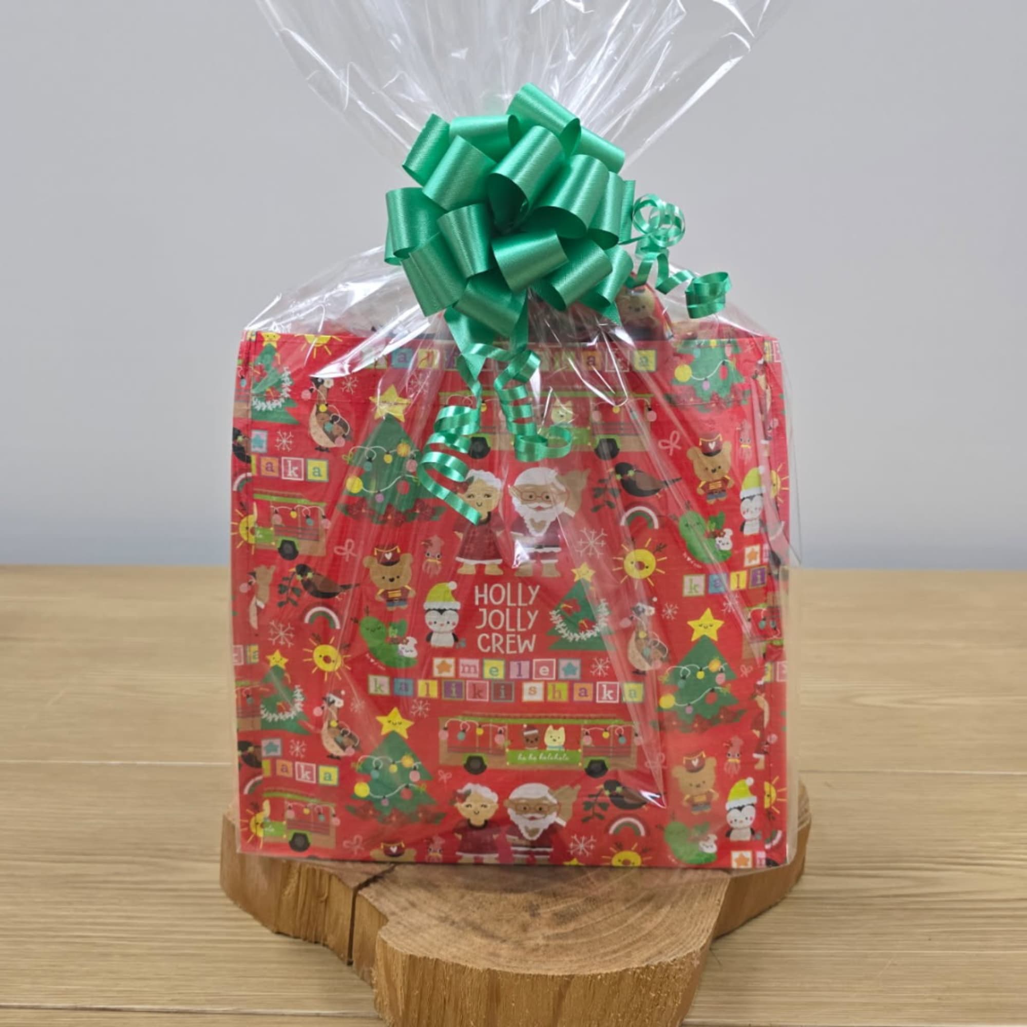 Wrapped Christmas gift bag with a green bow on a wooden base
