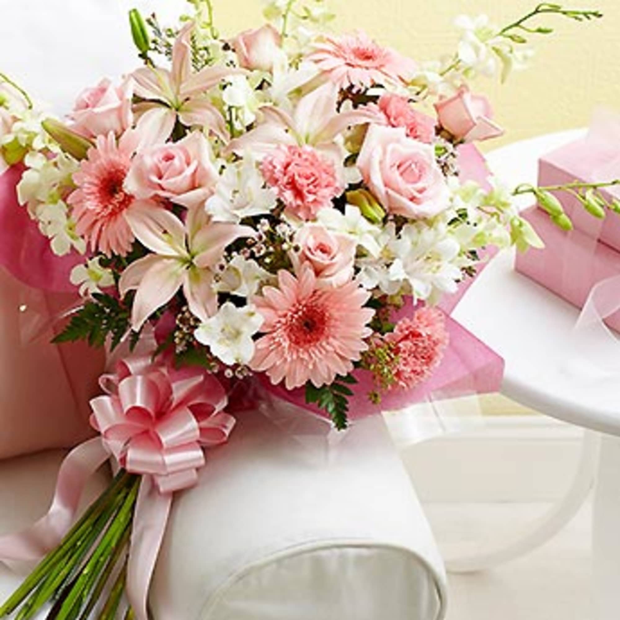 Pink and white bouquet with roses, lilies, and daisies tied with a ribbon