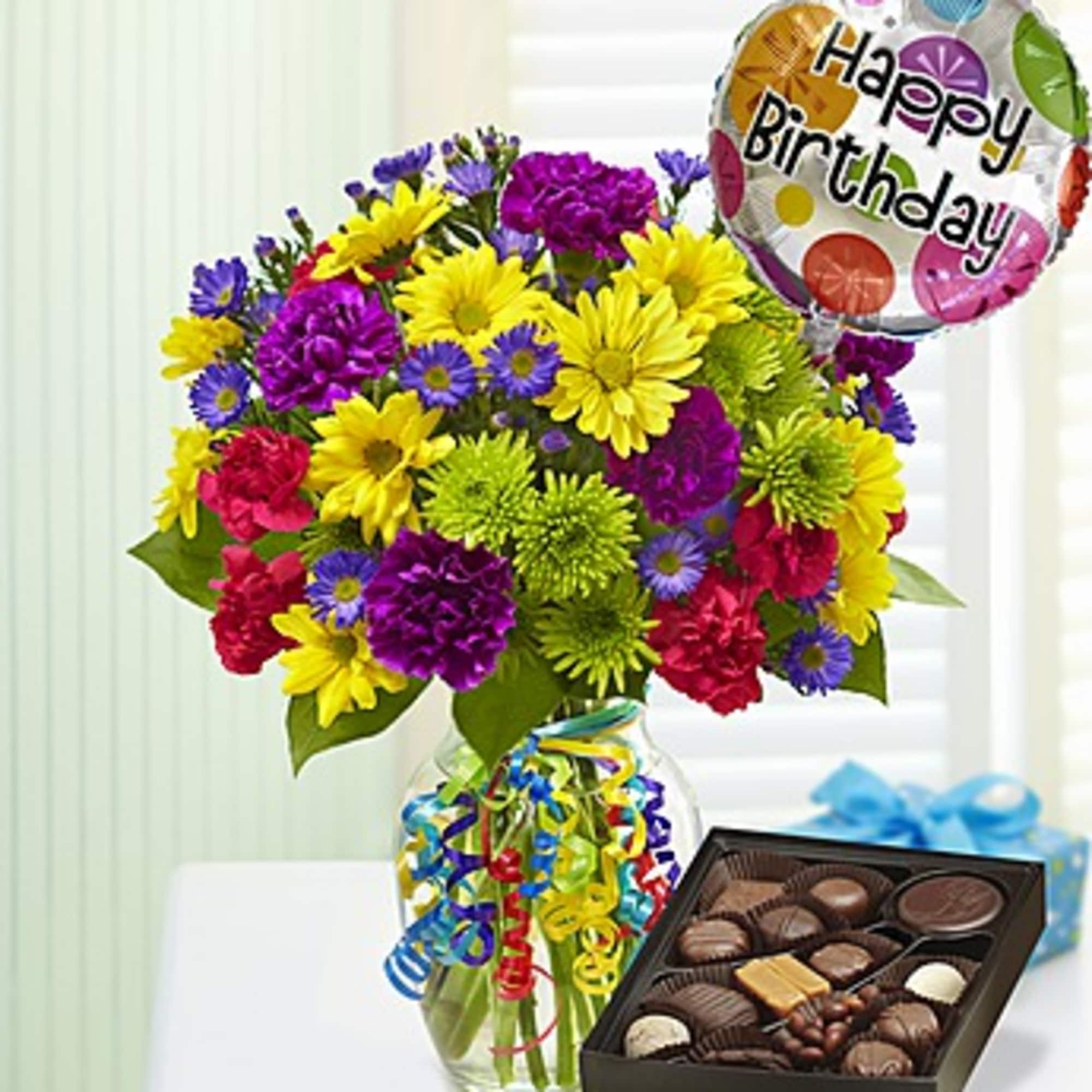 Colorful bouquet in a glass vase with a birthday balloon and box of chocolates