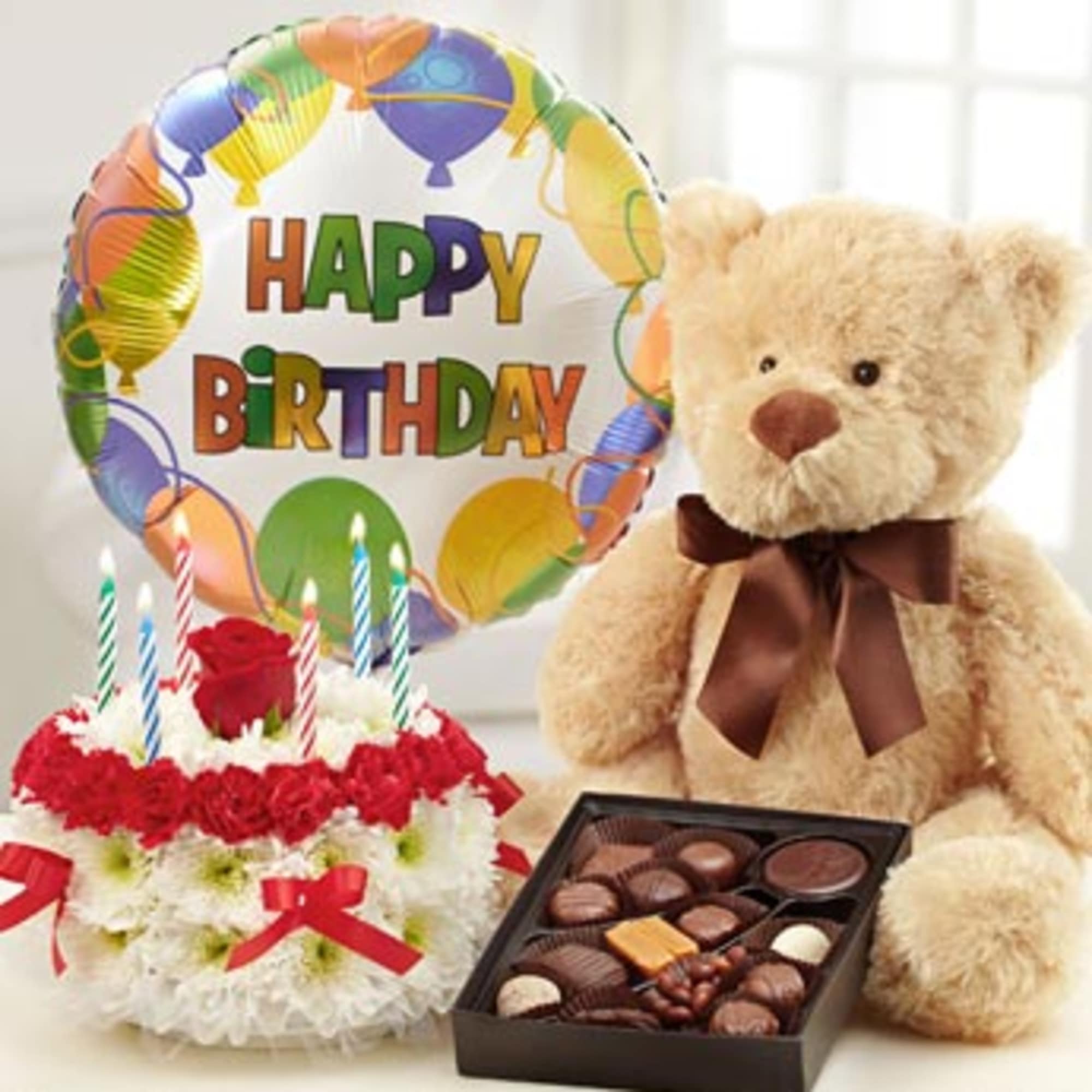 Birthday balloon, teddy bear, cake, and chocolates arranged together