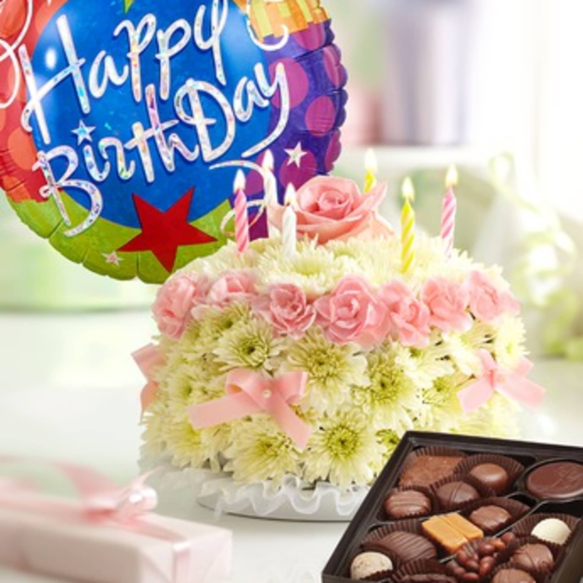 Birthday flower cake with pink roses, candles, and a balloon