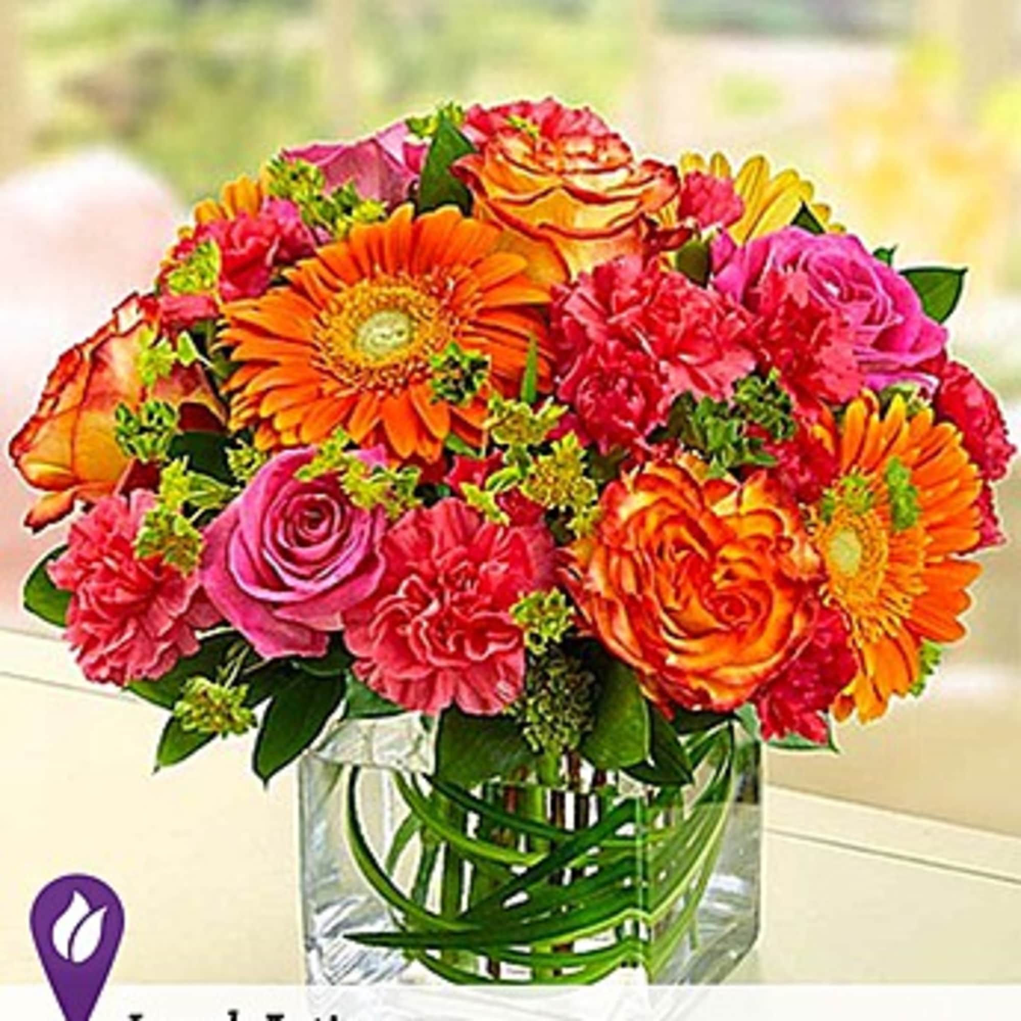 Bouquet of orange, pink, and red flowers in a clear glass vase