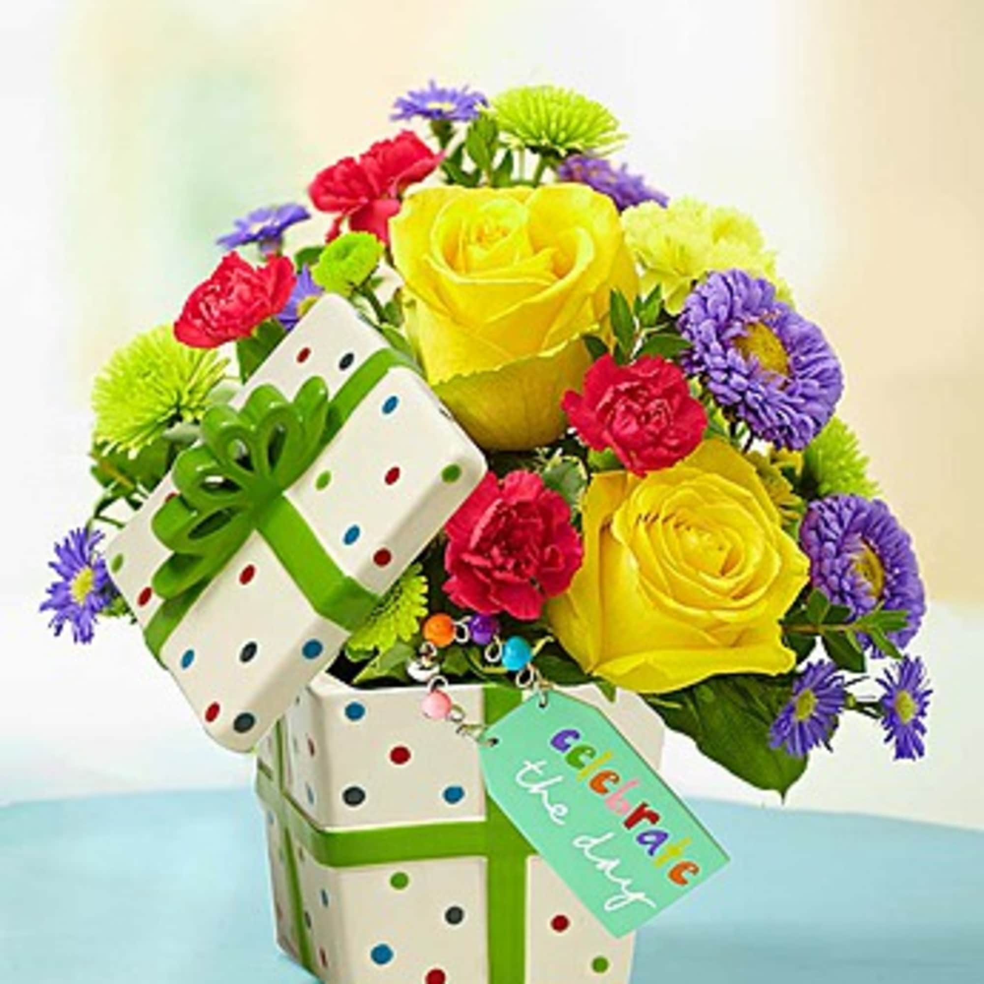Bouquet of yellow roses, red carnations, and purple daisies in a gift box