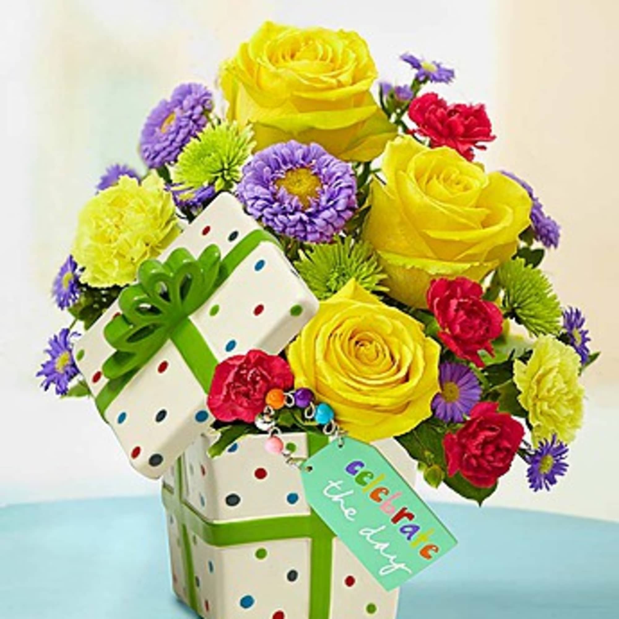 Yellow roses and colorful flowers in a polka-dot gift box