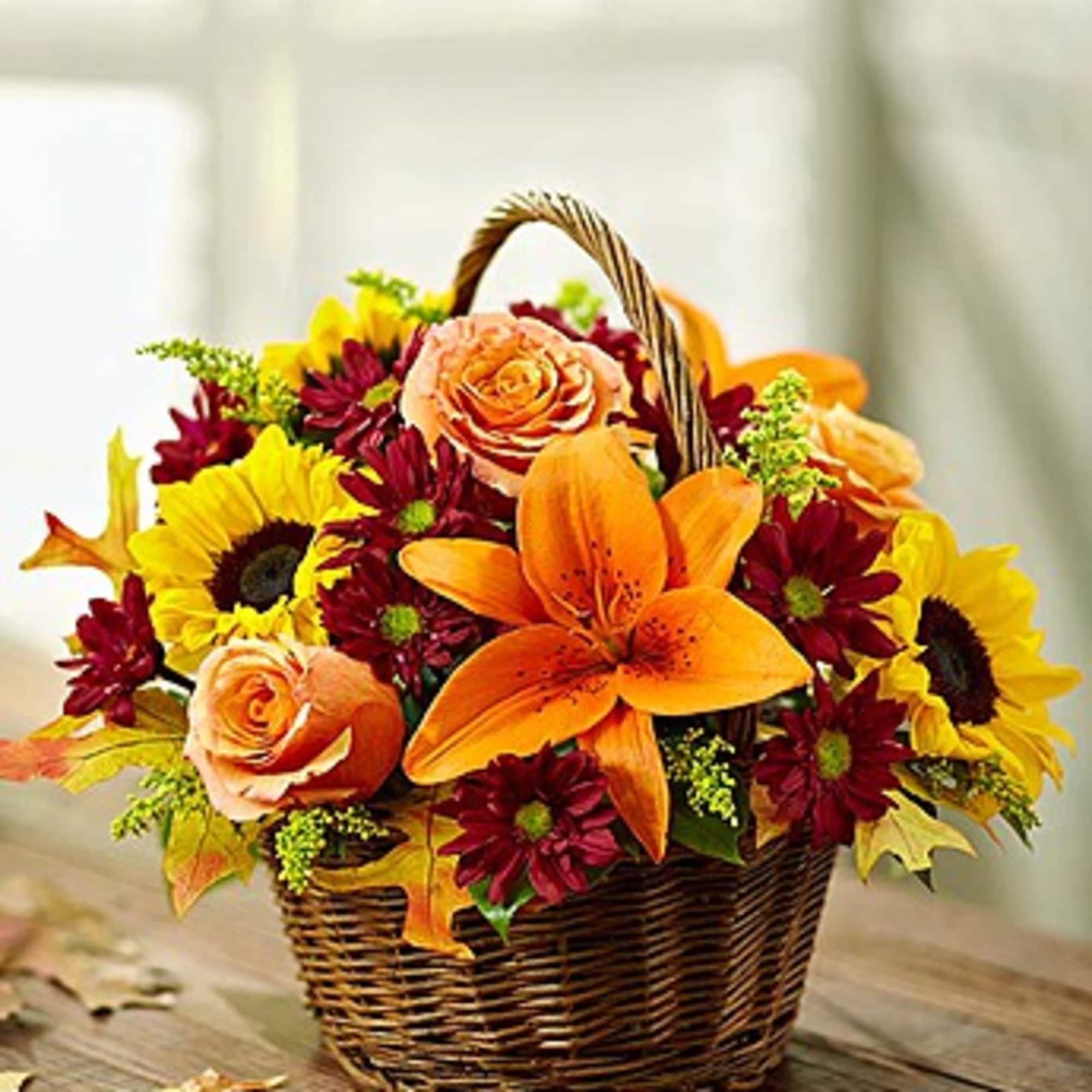 Basket of orange and yellow flowers with burgundy blooms