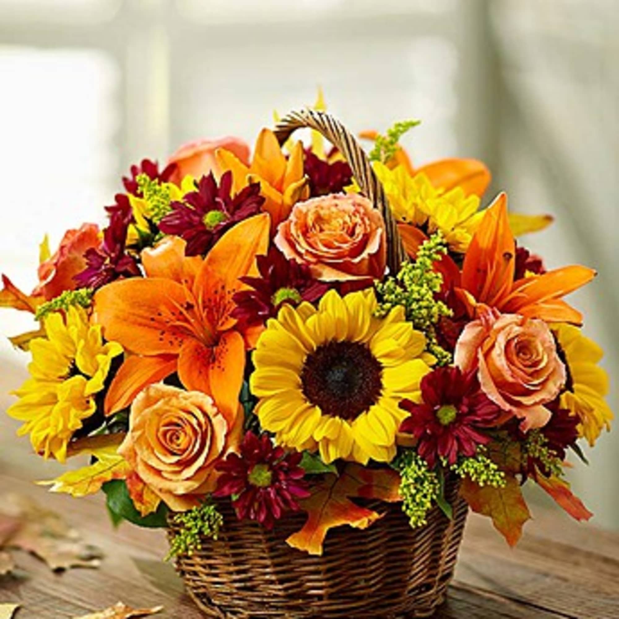 Basket arrangement of sunflowers, orange lilies, and roses