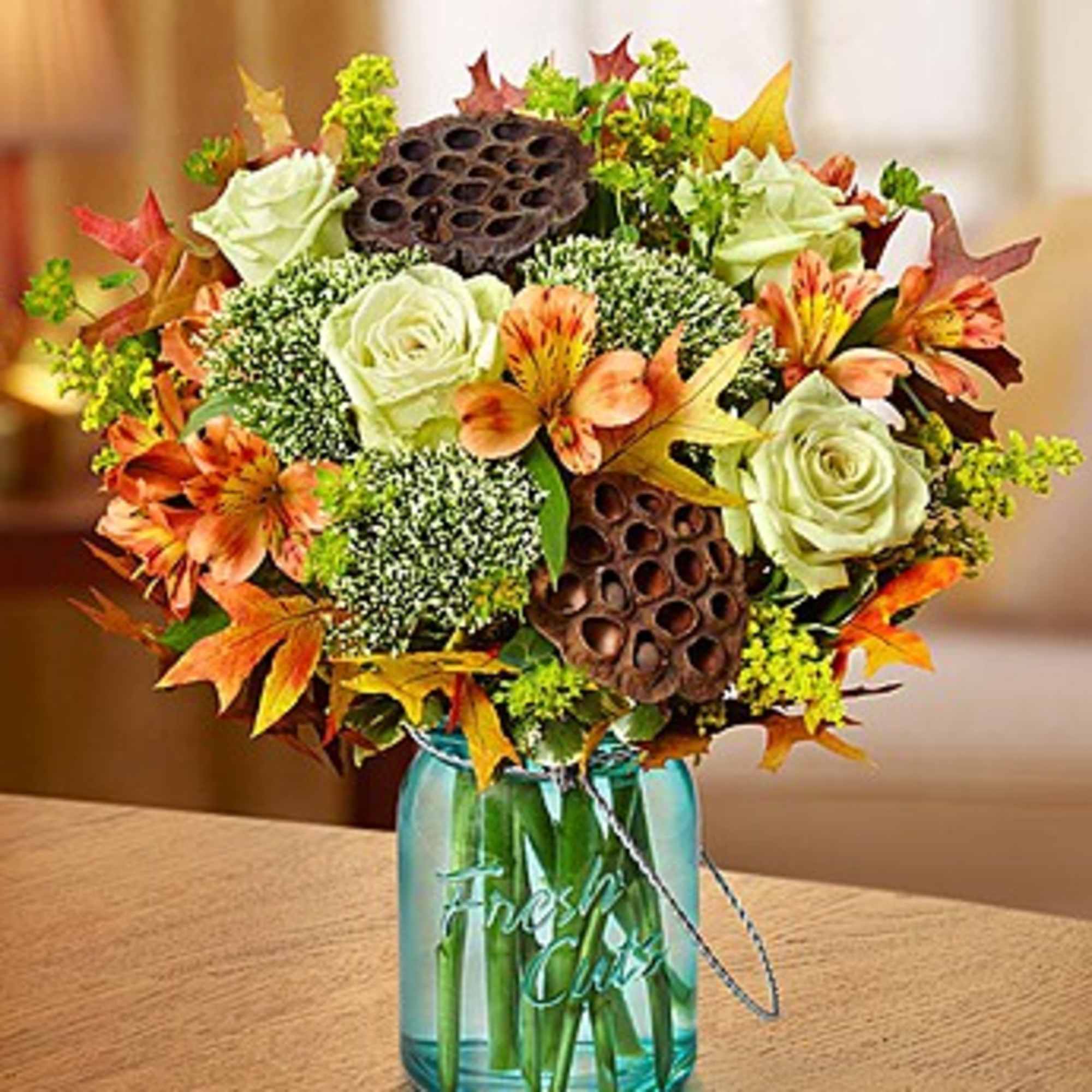 Bouquet of white roses and orange flowers in a blue glass vase