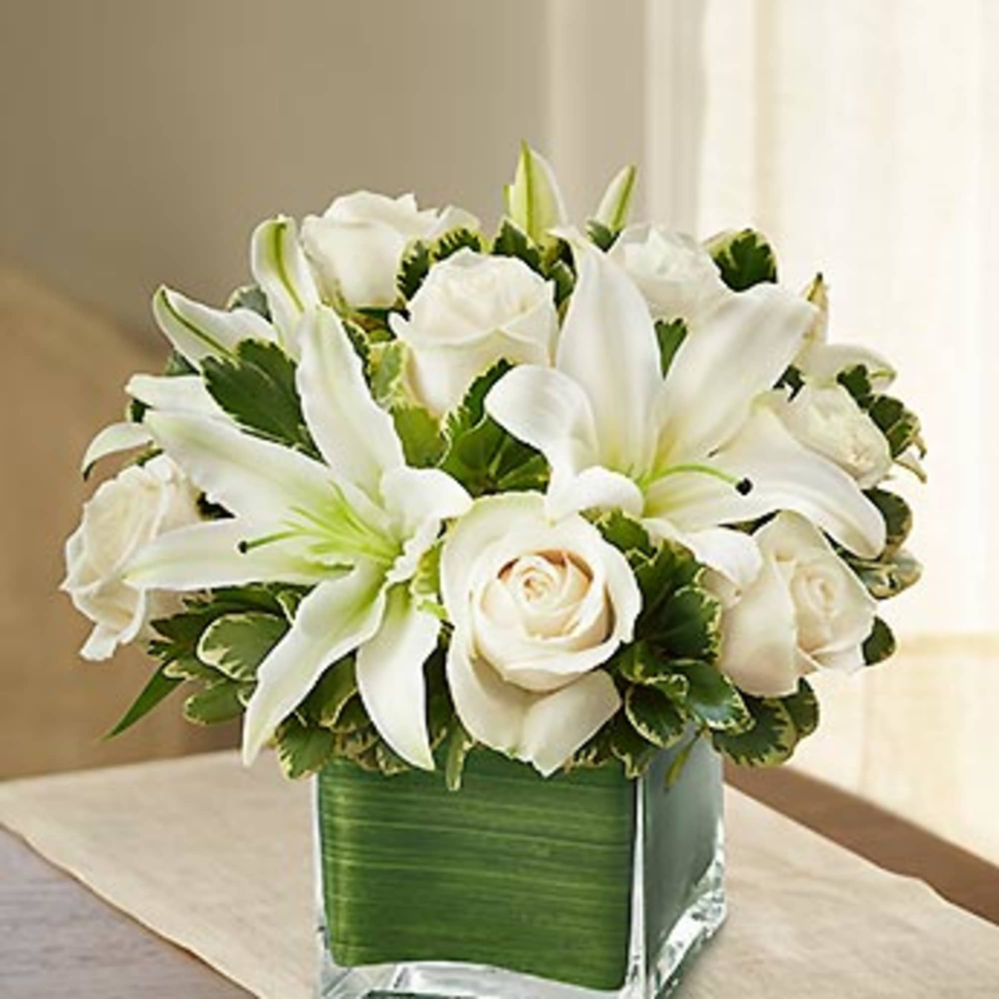 White lilies and roses in a square glass vase
