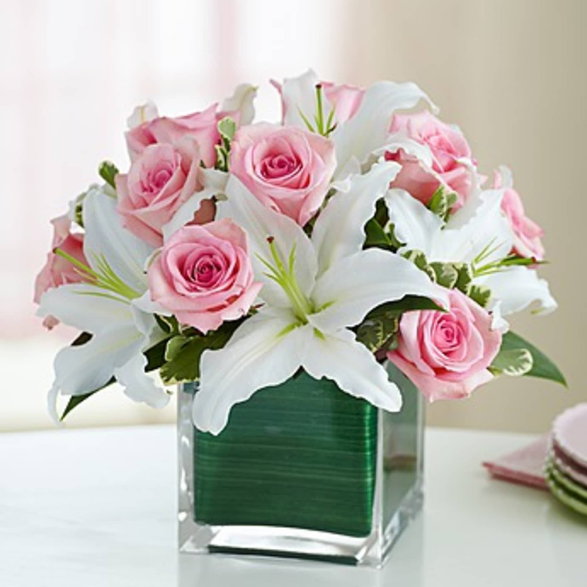 Pink roses and white lilies arranged in a clear square vase, photo 2 of 3