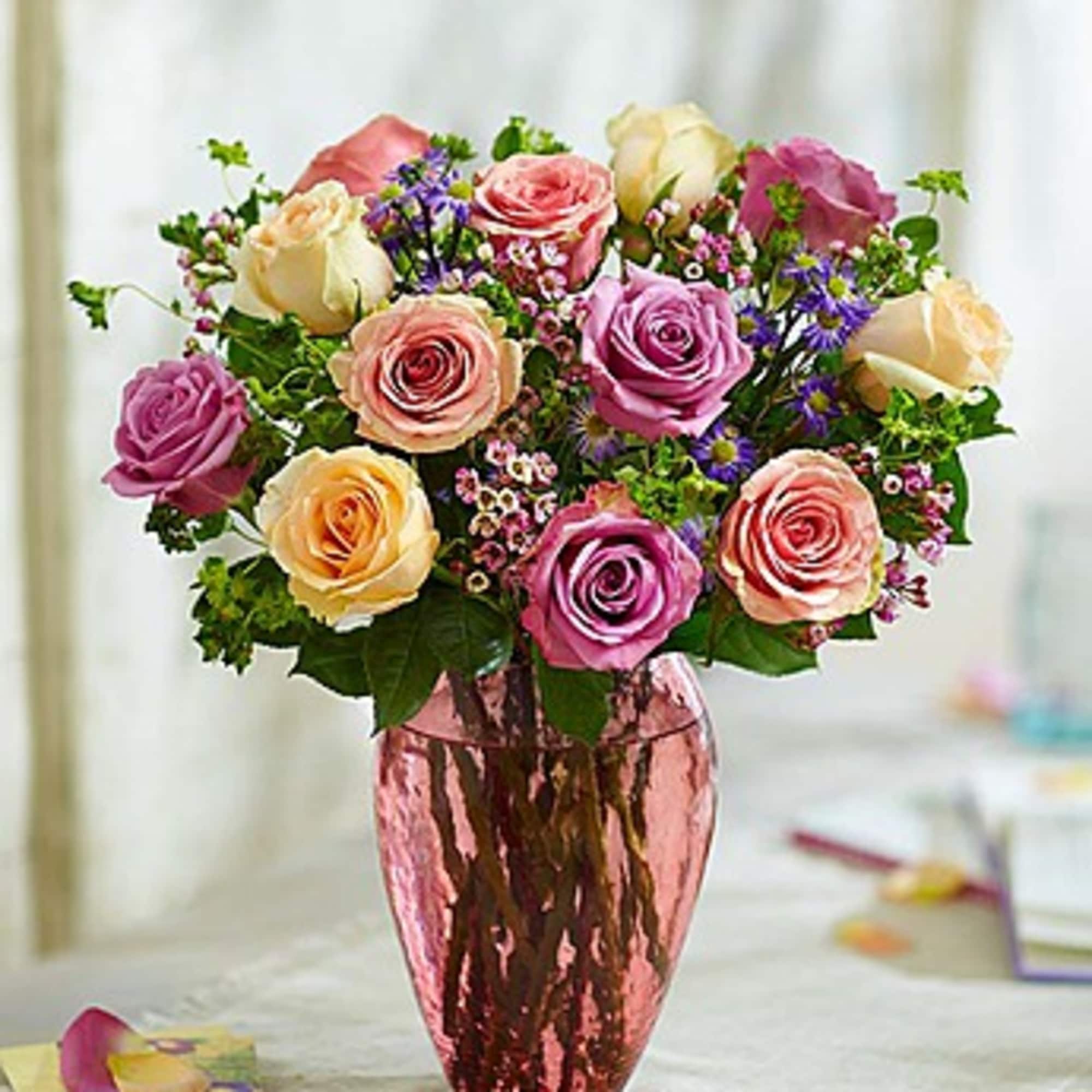 Bouquet of pink, cream, and purple roses in a metallic vase