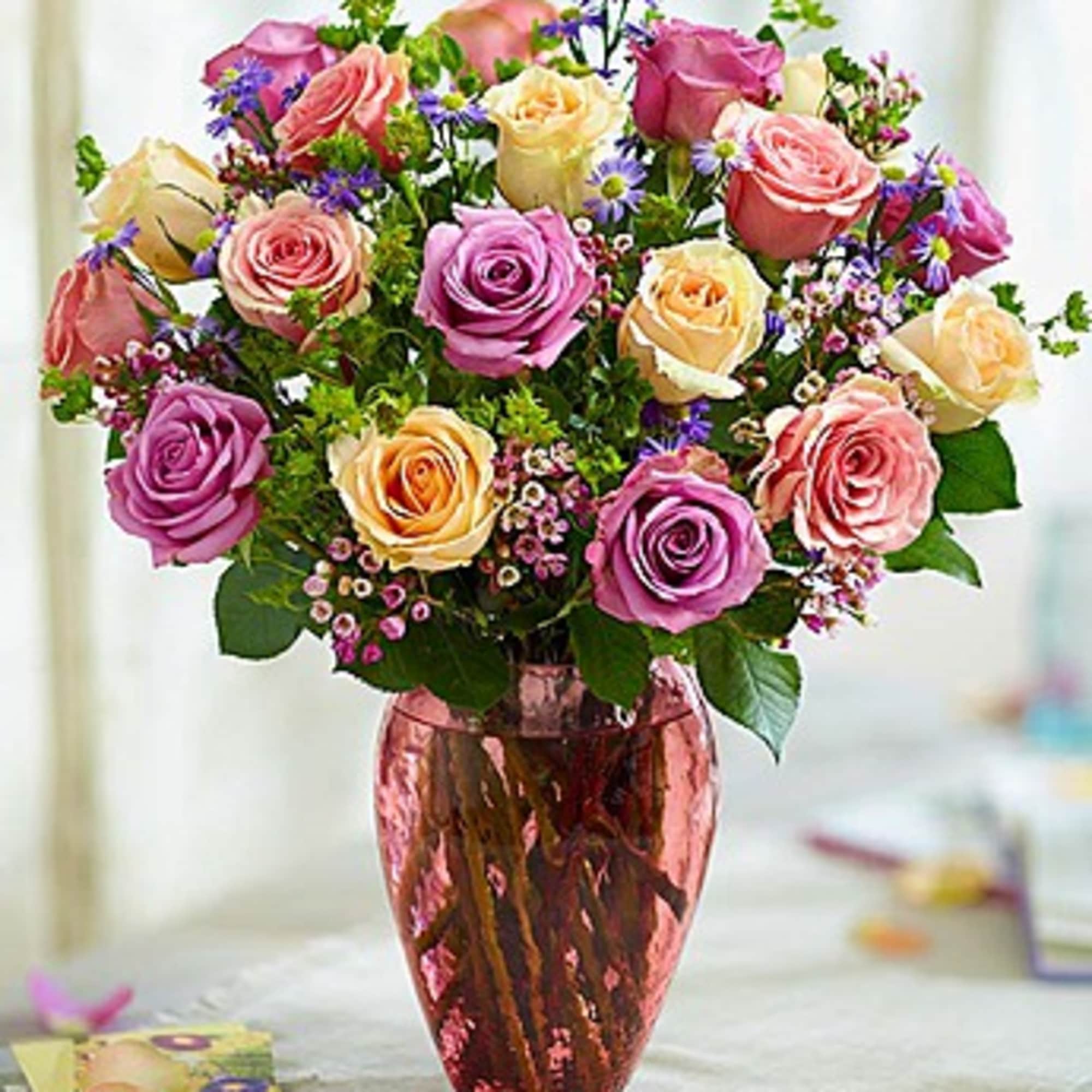 Bouquet of pink, lavender, and cream roses in a pink vase