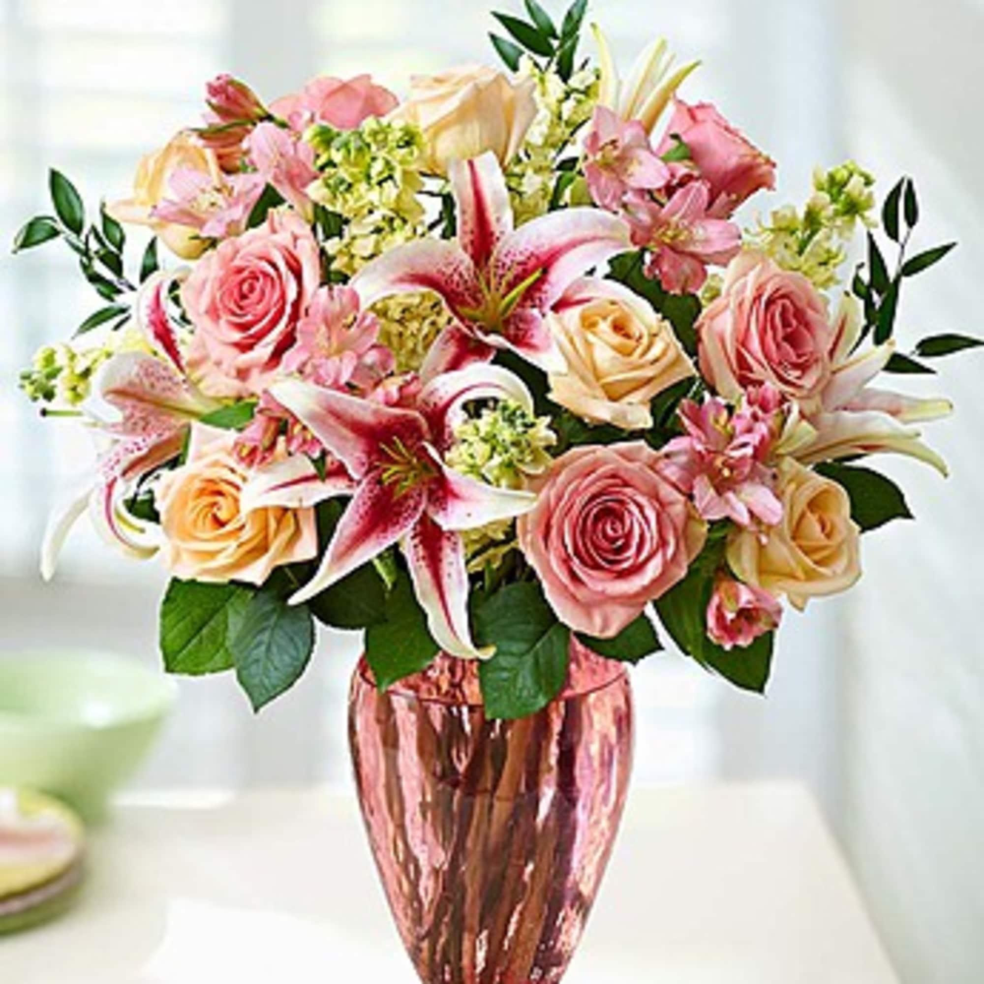 Pink and peach roses with lilies in a pink glass vase, photo 2 of 3