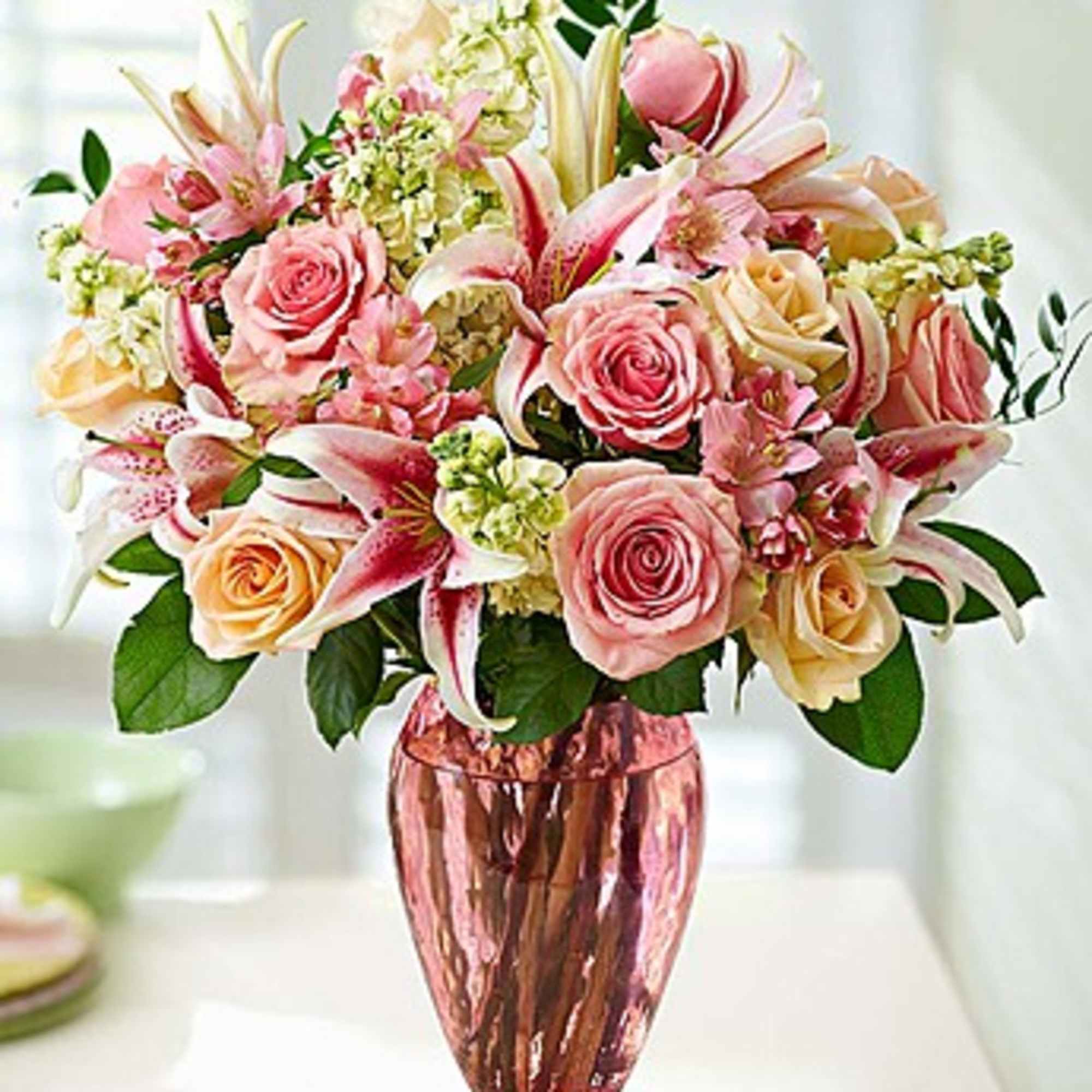 Pink and cream bouquet of roses and lilies in a metallic vase