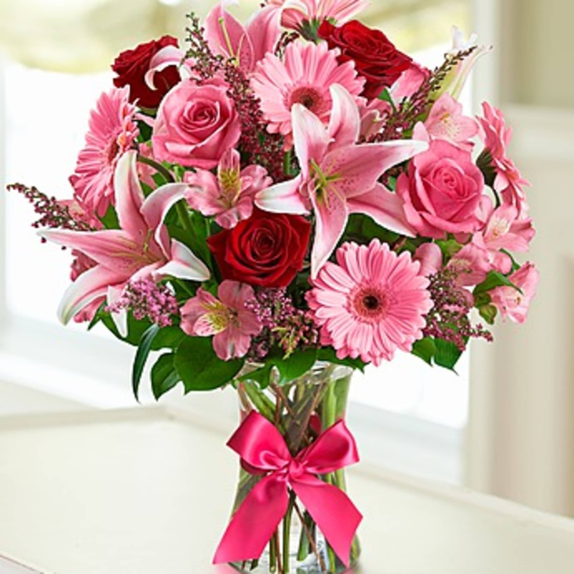 Pink and red mixed bouquet in a glass vase with a ribbon