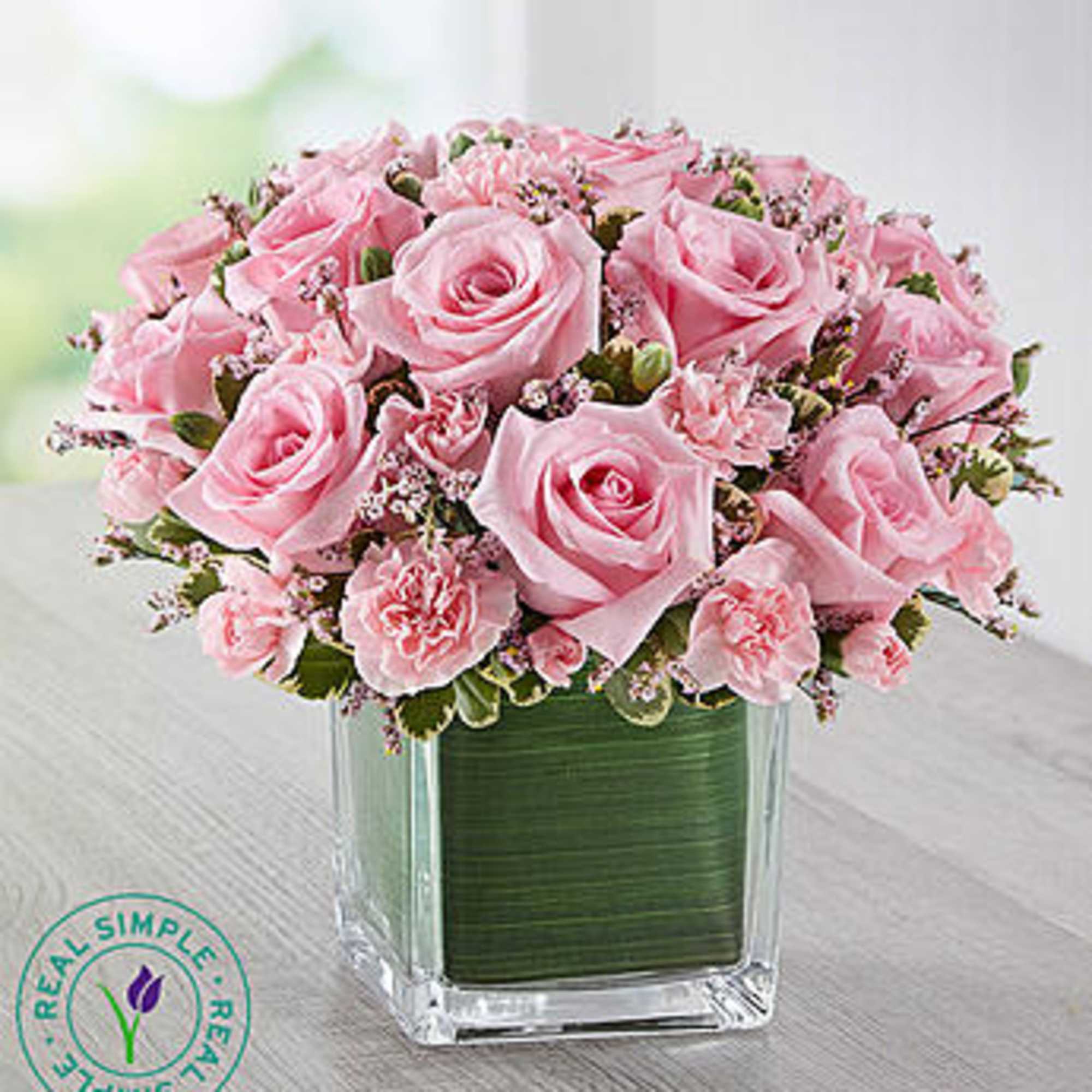 Pink roses and carnations arranged in a square glass vase