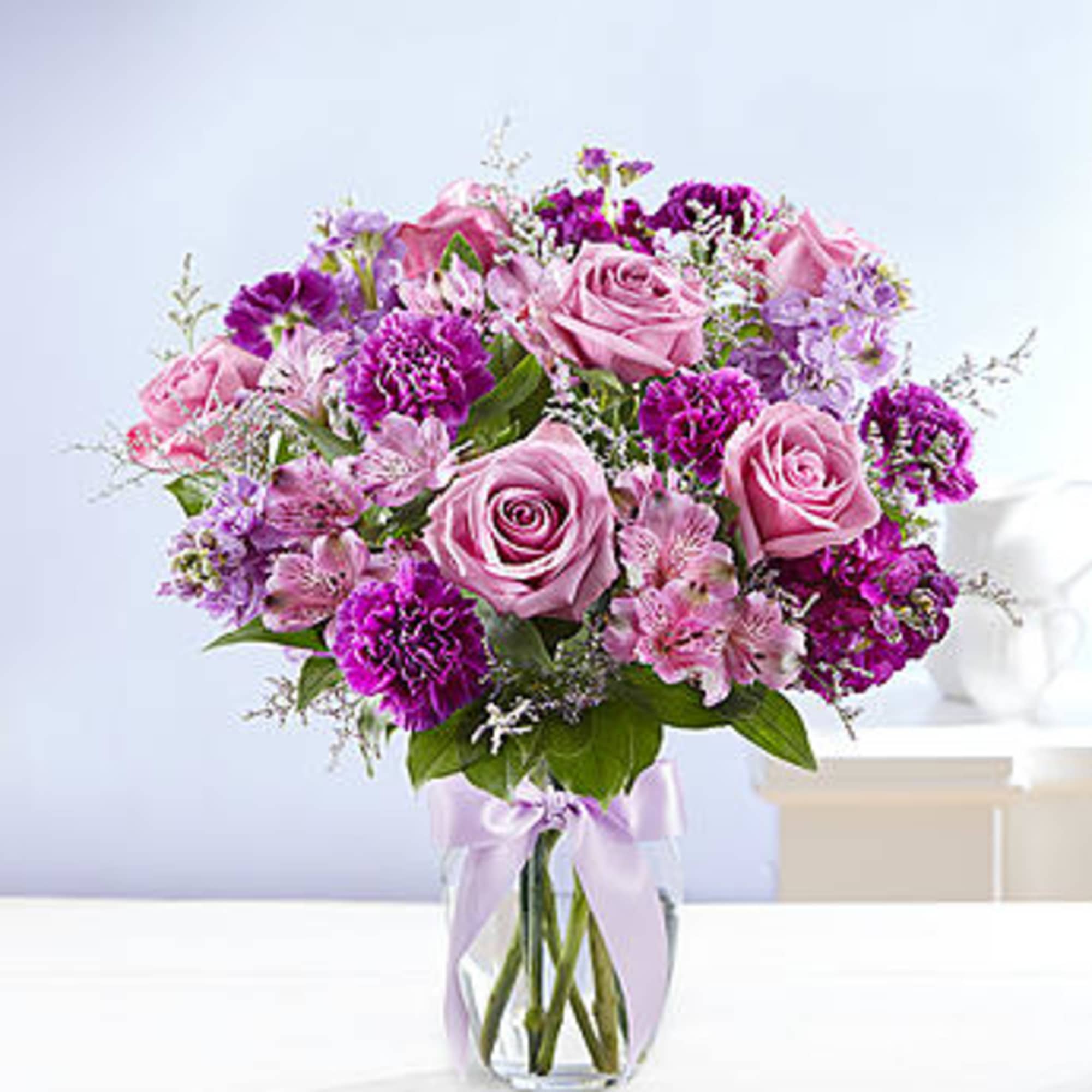 Pink and purple bouquet of roses and carnations in a glass vase