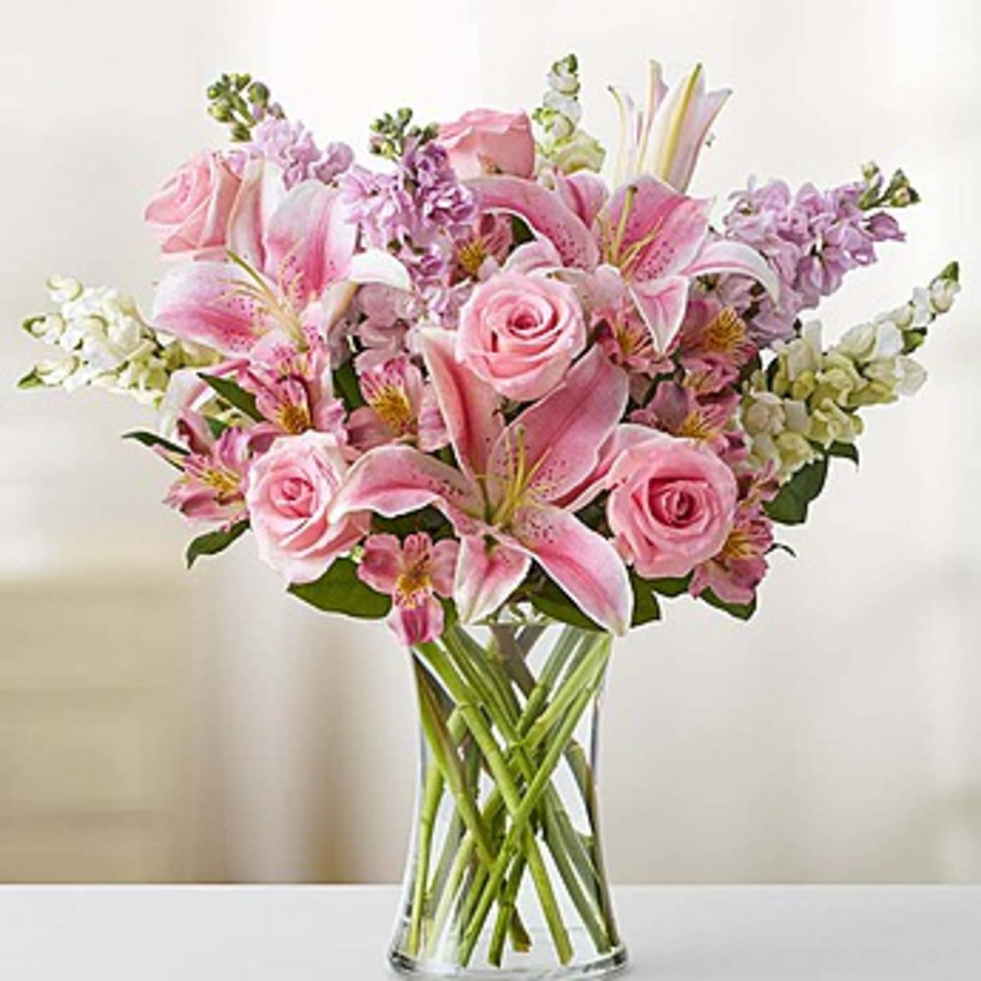 Pink lilies and roses arranged in a clear glass vase, photo 3 of 3
