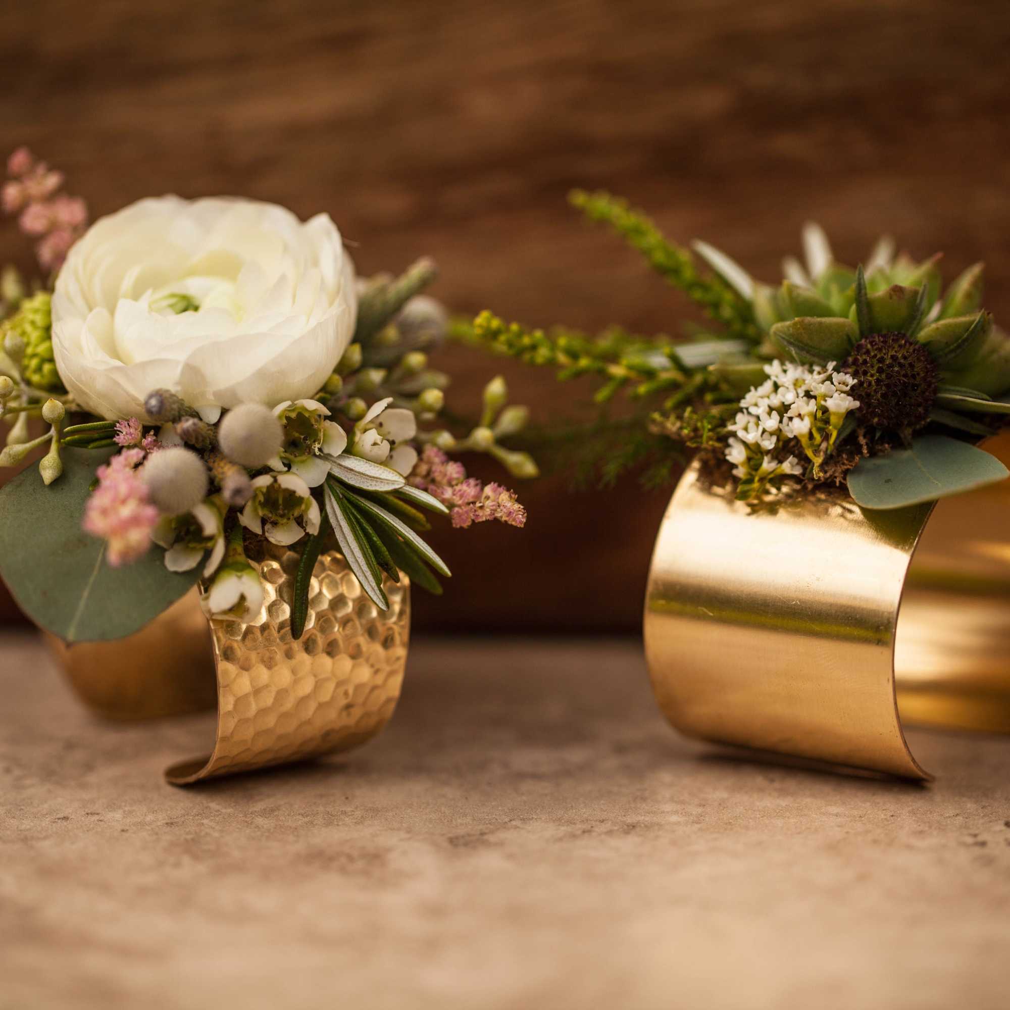 Two floral wrist corsages with gold cuffs and white blooms
