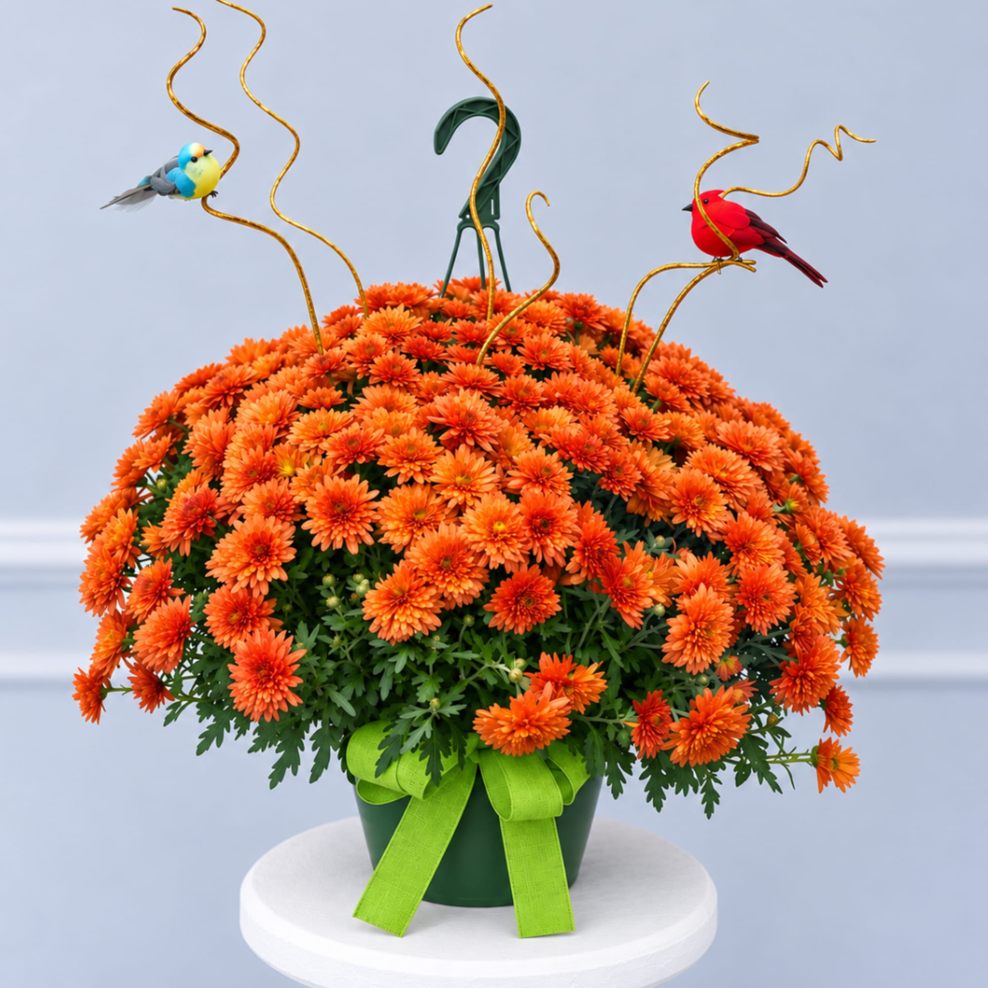 Orange chrysanthemum arrangement in a green pot with bird picks