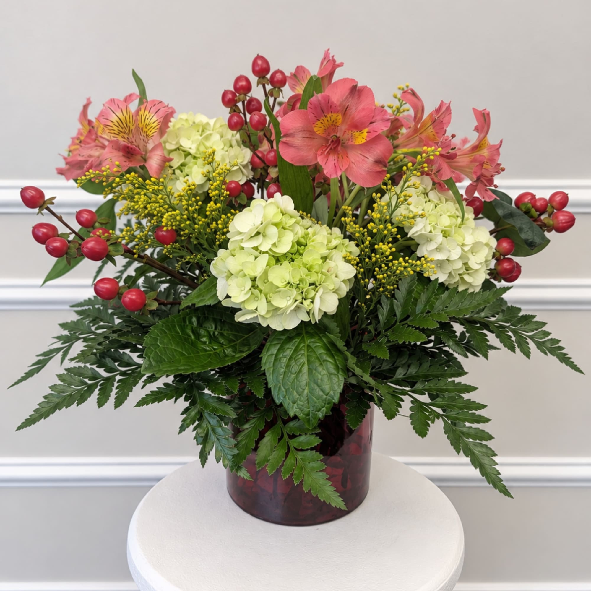 Pink alstroemeria and pale hydrangeas in a red vase