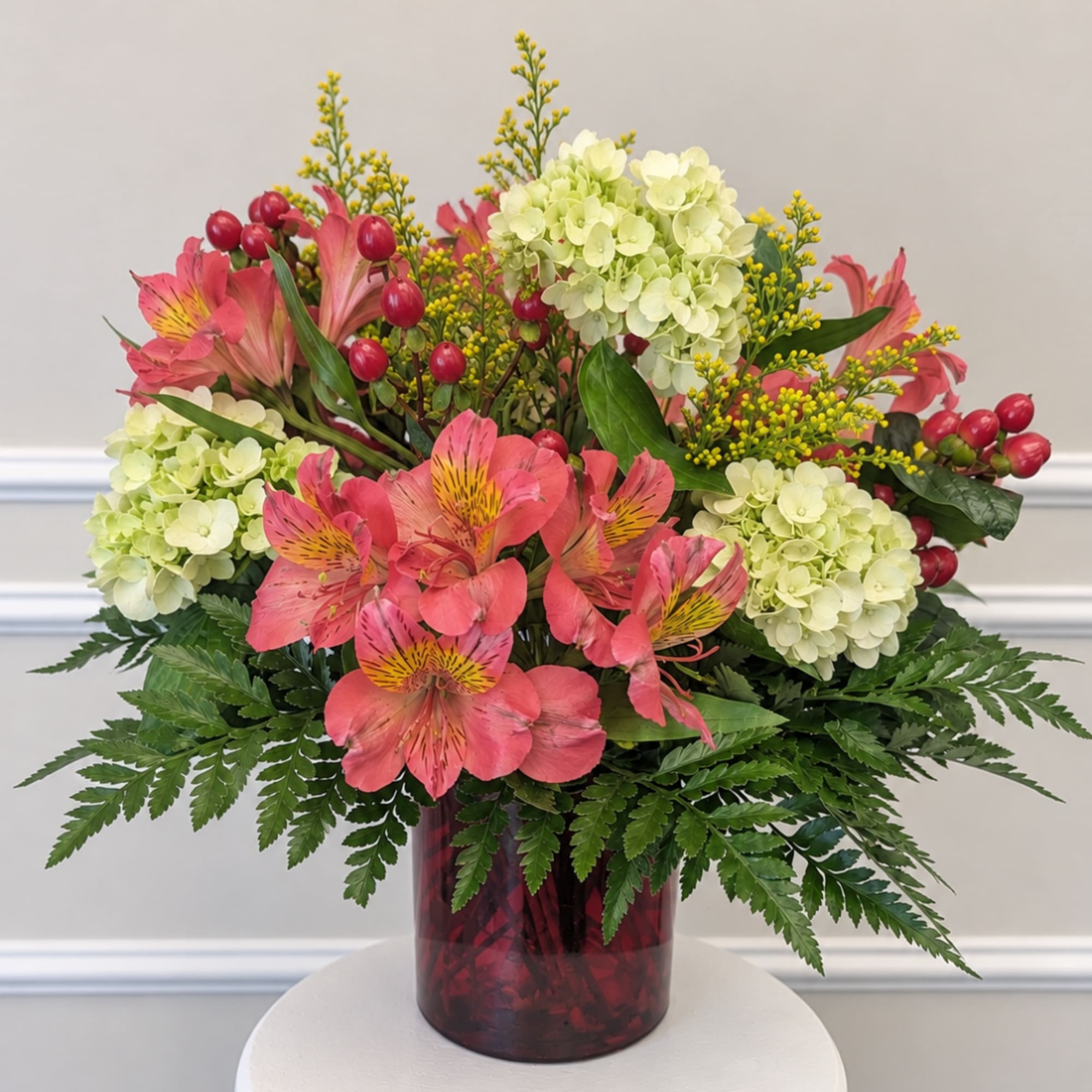 Pink alstroemeria and pale hydrangeas in a red glass vase